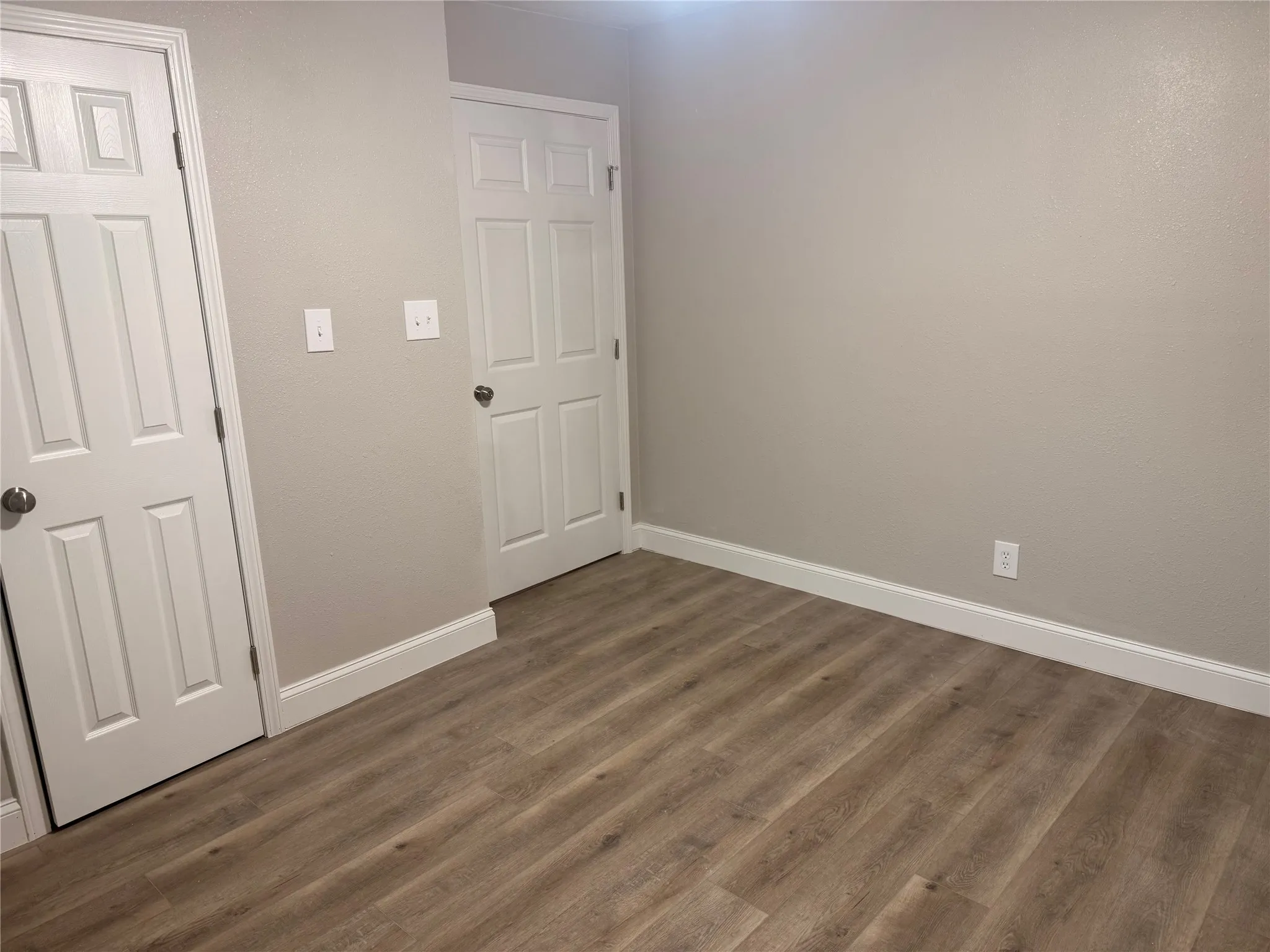 Spare room with baseboards and dark wood-style floors