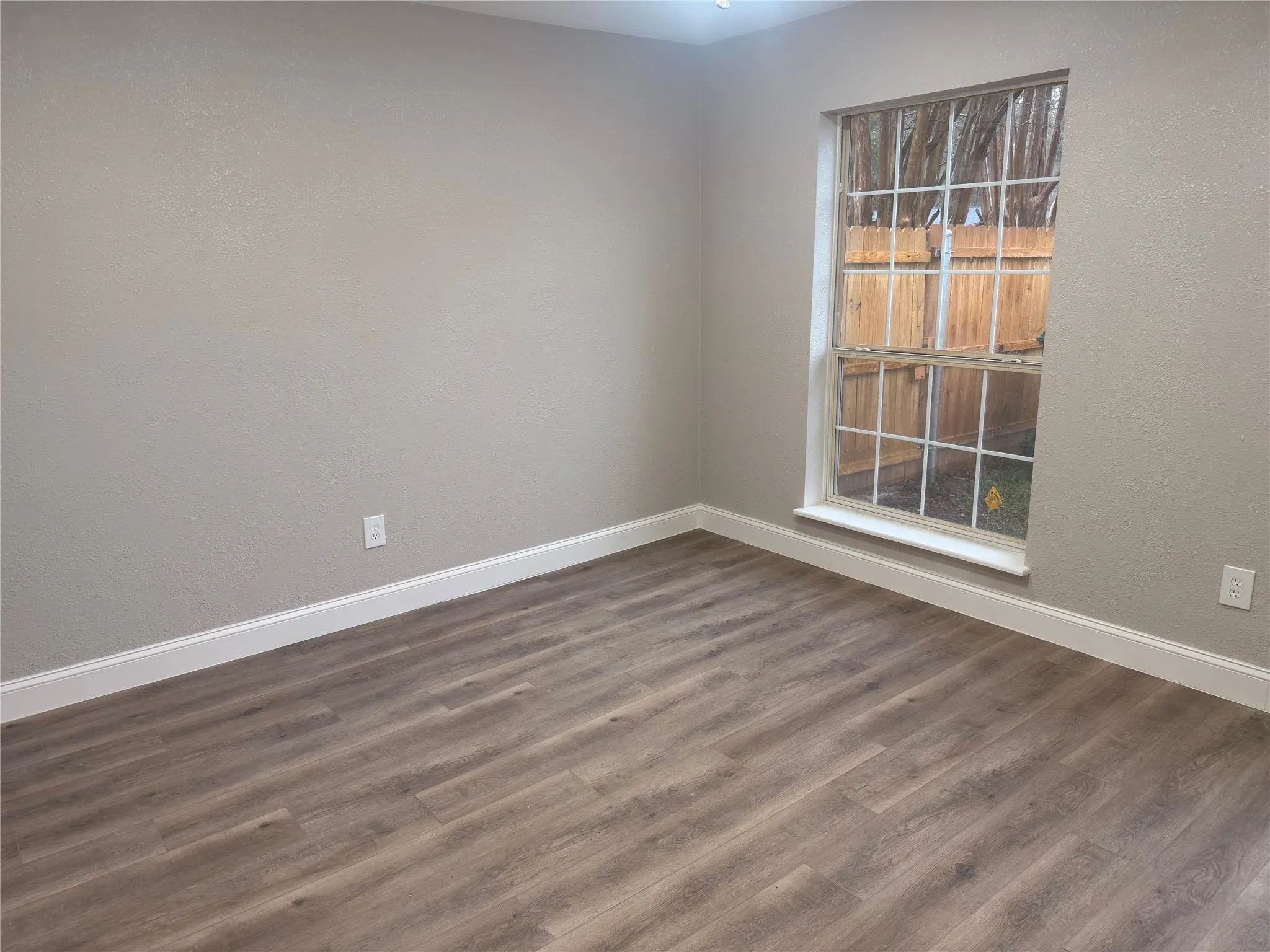 Unfurnished room with dark wood-type flooring and a textured wall