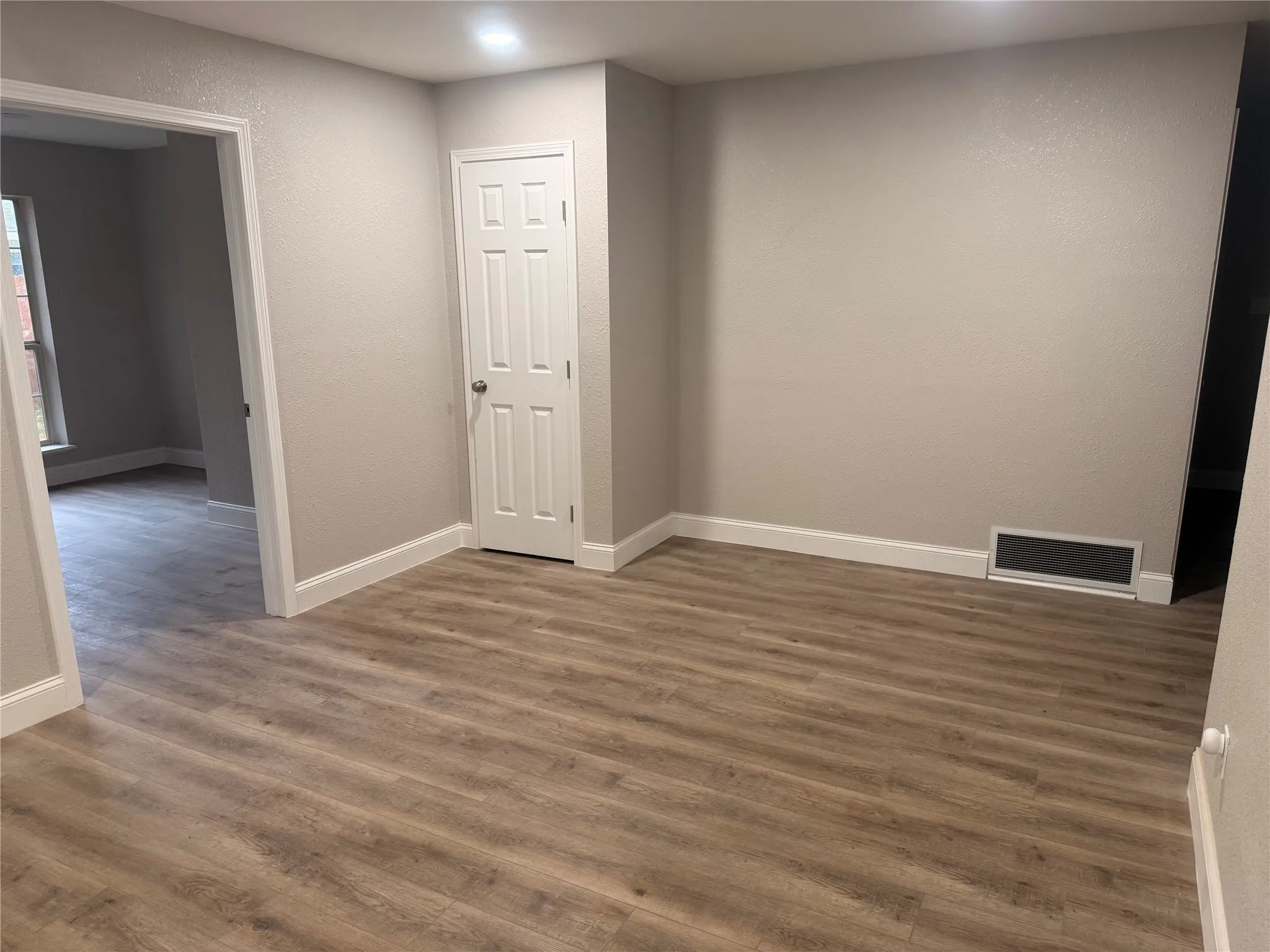 Spare room featuring dark wood-style floors, recessed lighting, and a textured wall