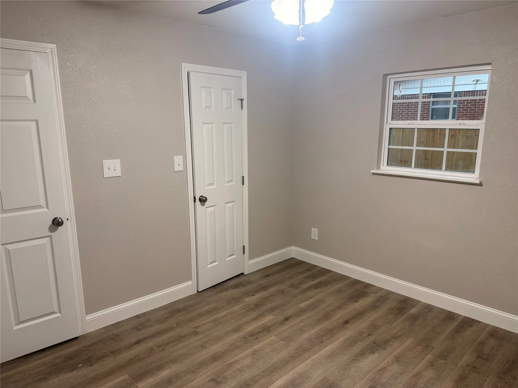 Unfurnished bedroom featuring dark wood finished floors, ceiling fan, and a textured wall
