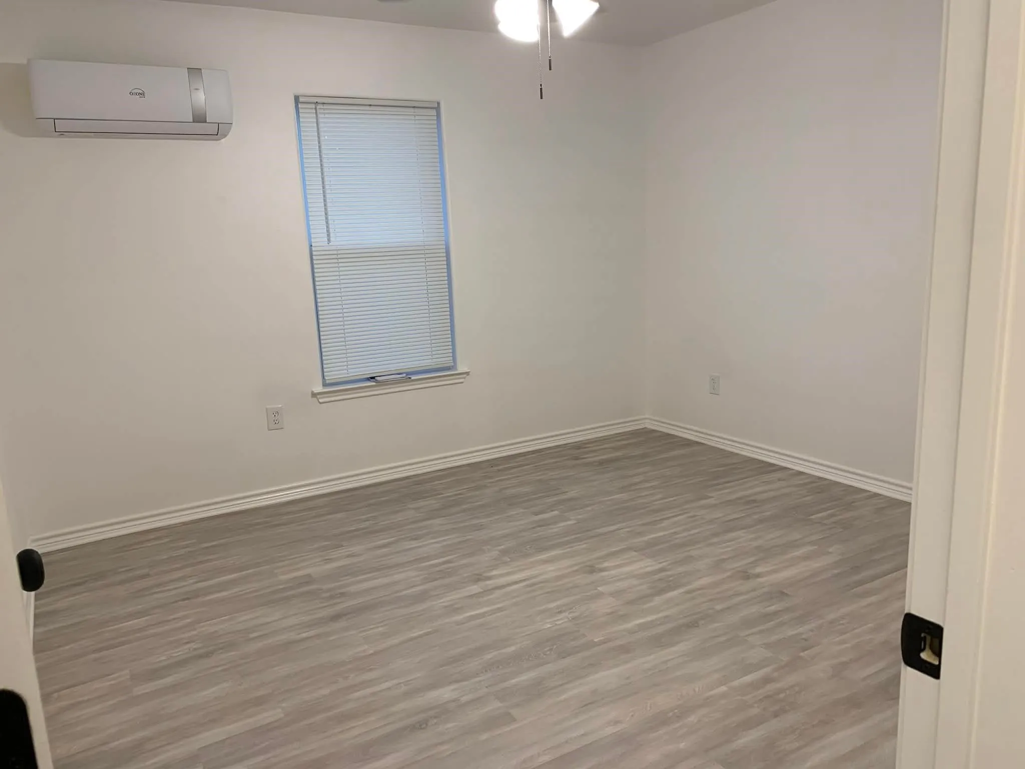 Unfurnished room with wood finished floors, a wall mounted air conditioner, and ceiling fan