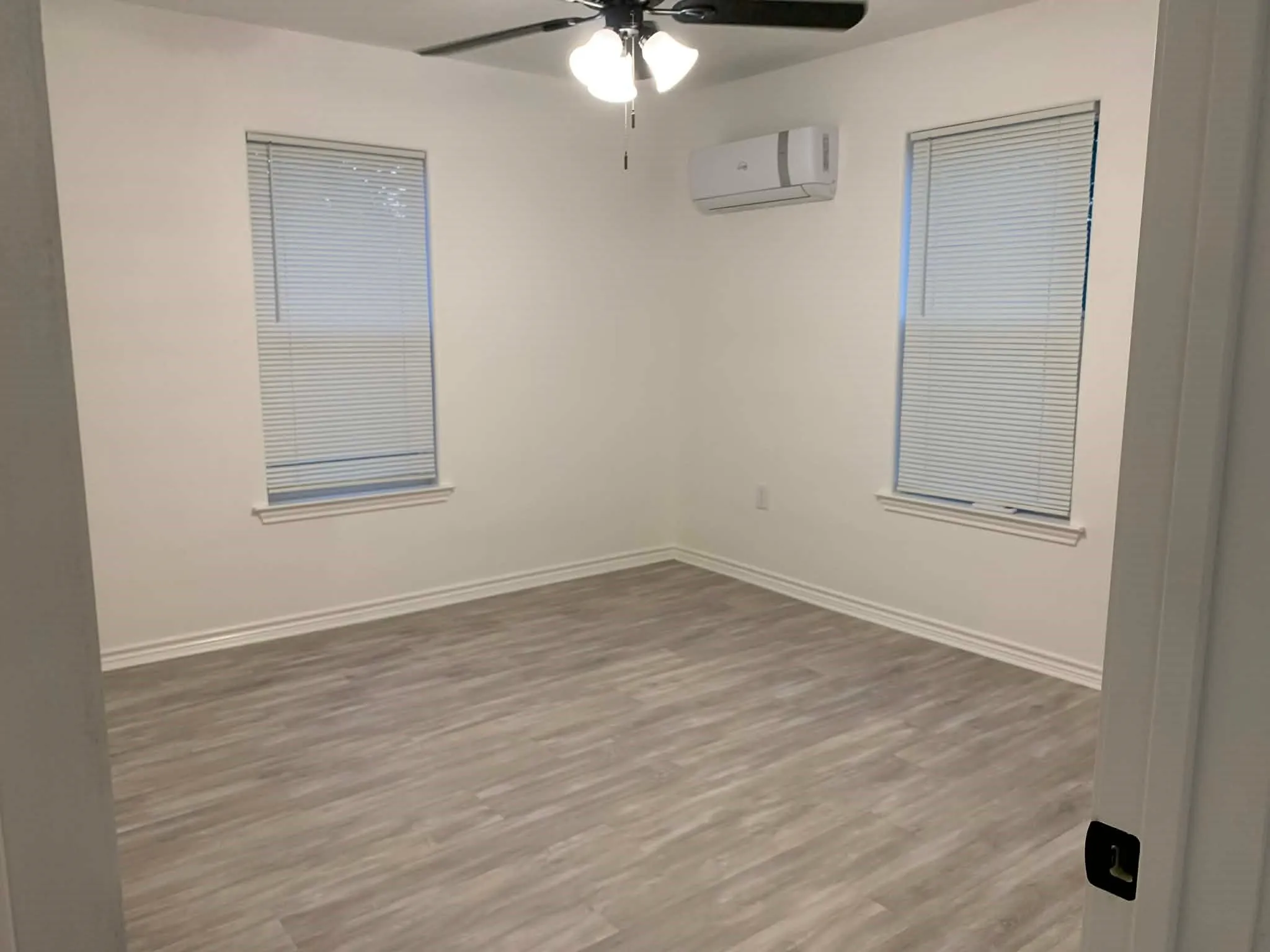 Unfurnished room with wood finished floors, a wall mounted air conditioner, and a ceiling fan