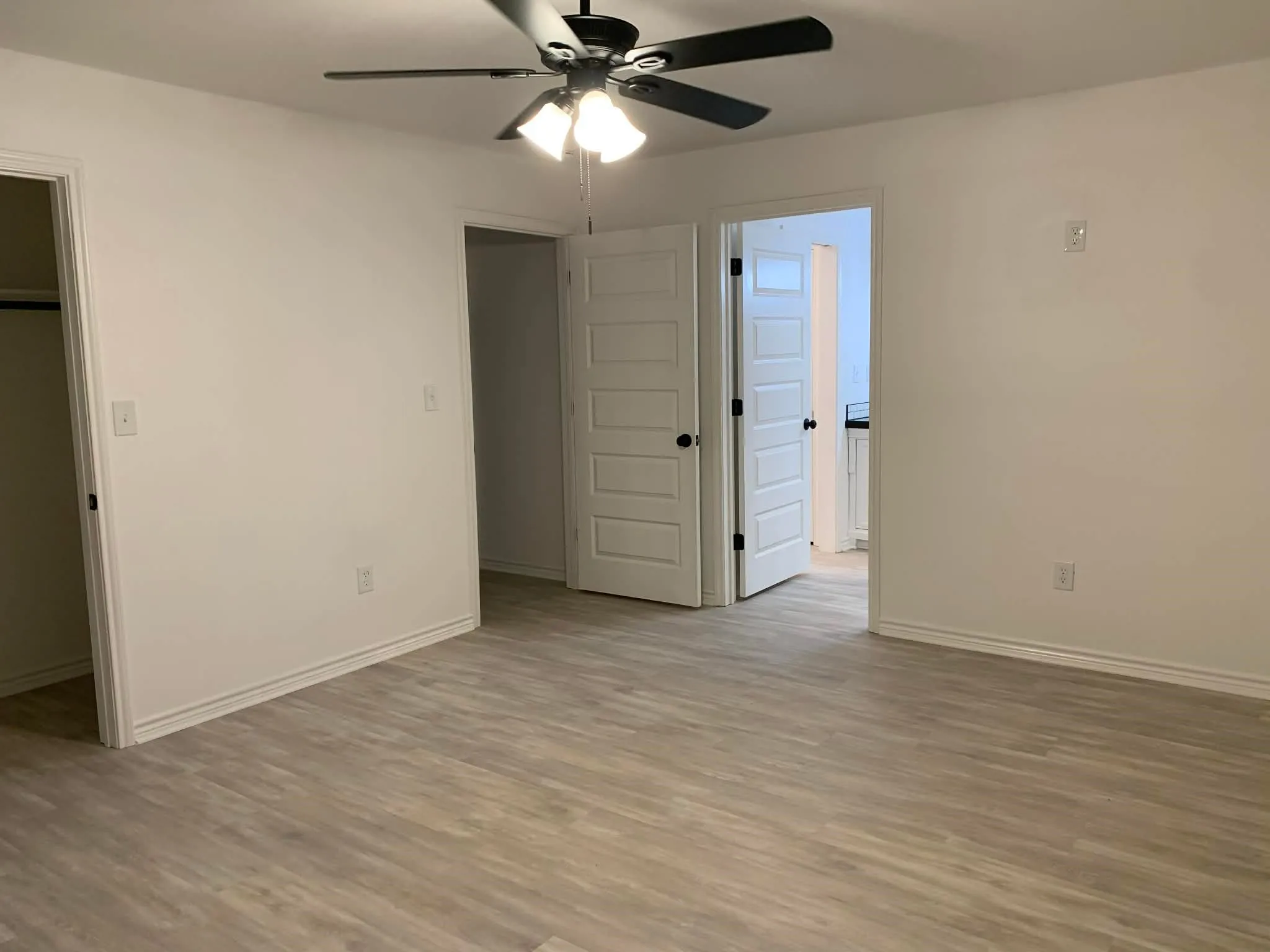Unfurnished bedroom with light wood finished floors, ceiling fan, and a walk in closet