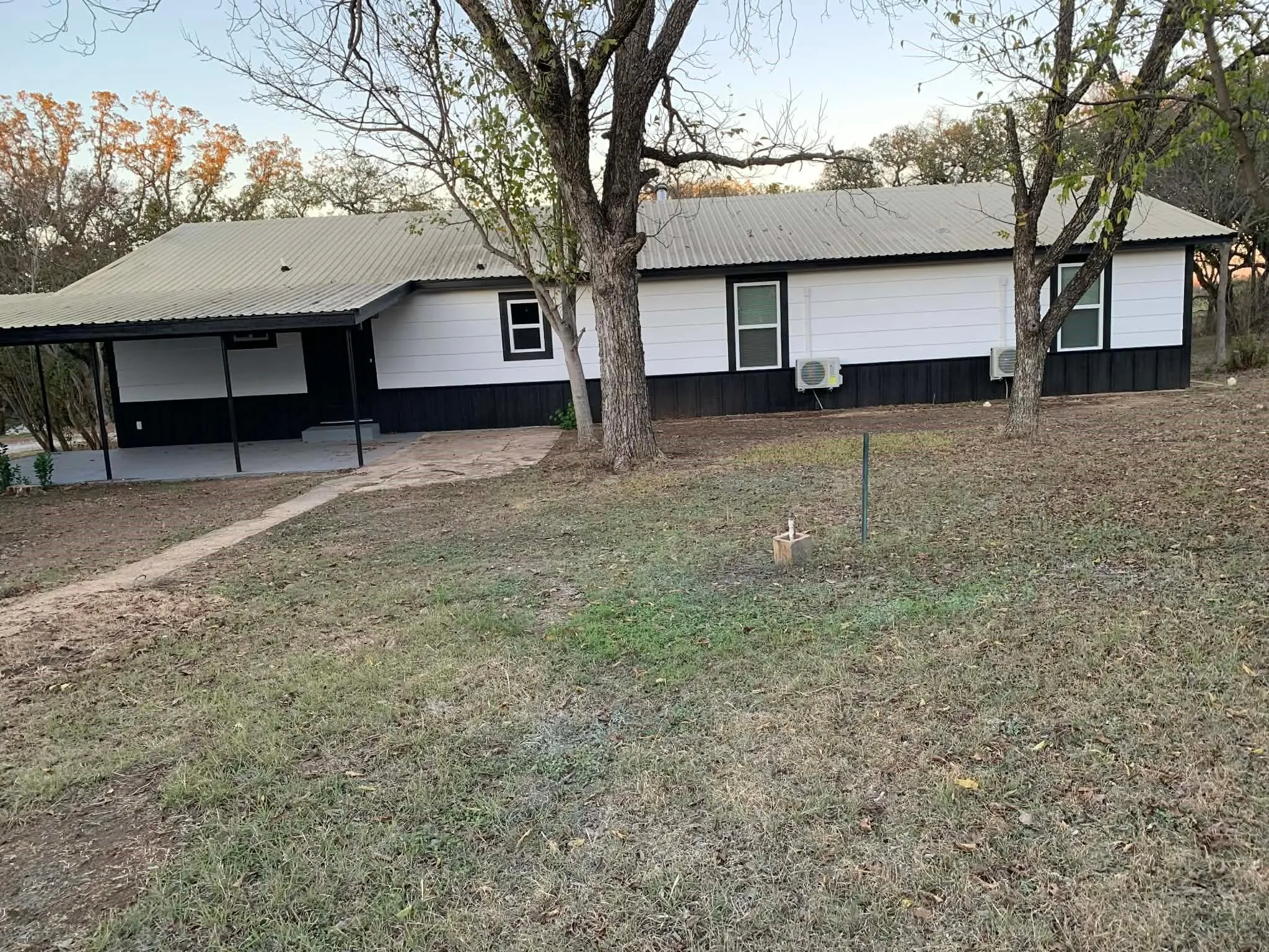 View of front facade featuring a patio area, a front lawn, a metal roof, and a carport