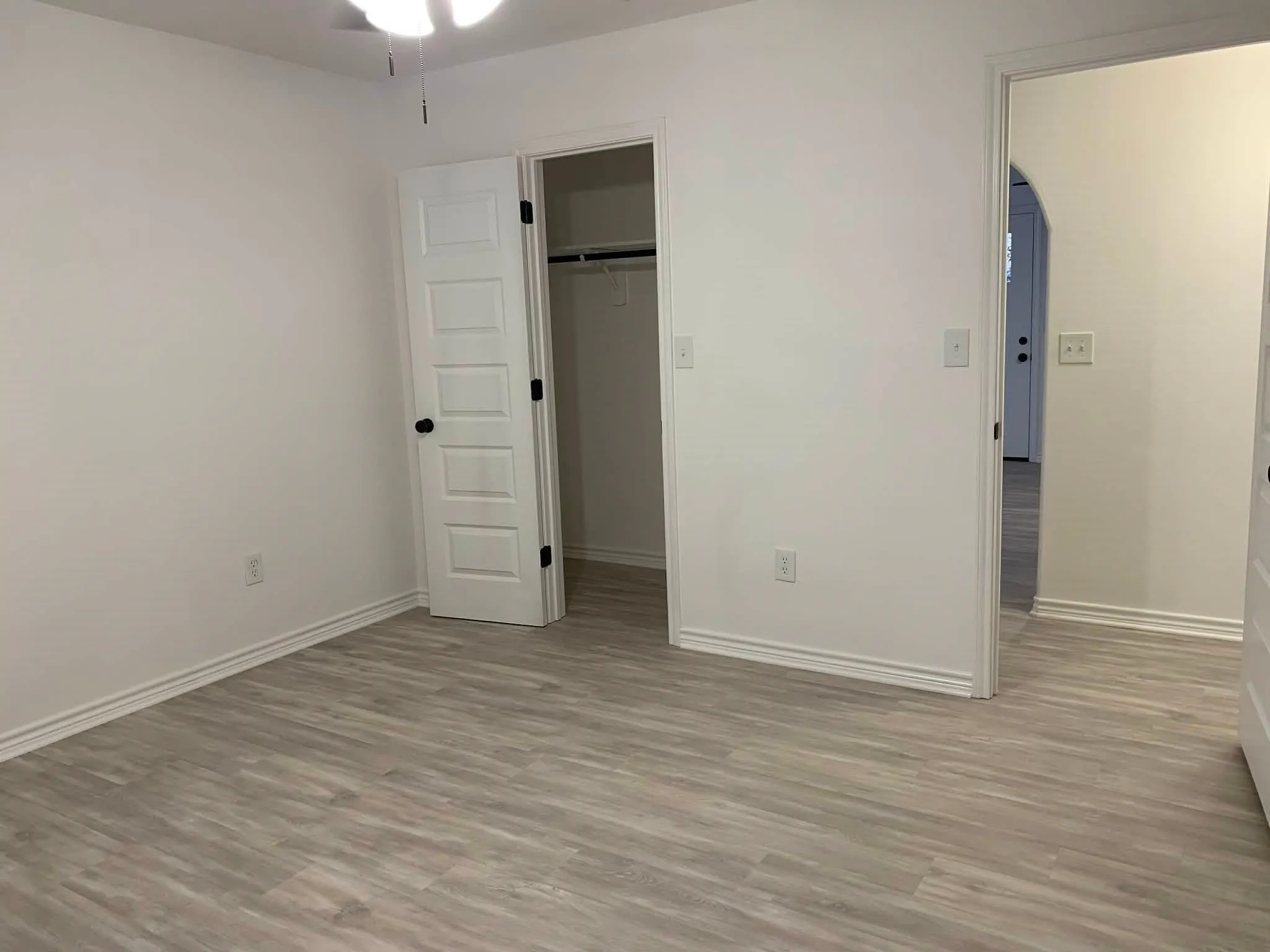 Unfurnished bedroom featuring light wood-type flooring, a spacious closet, and arched walkways