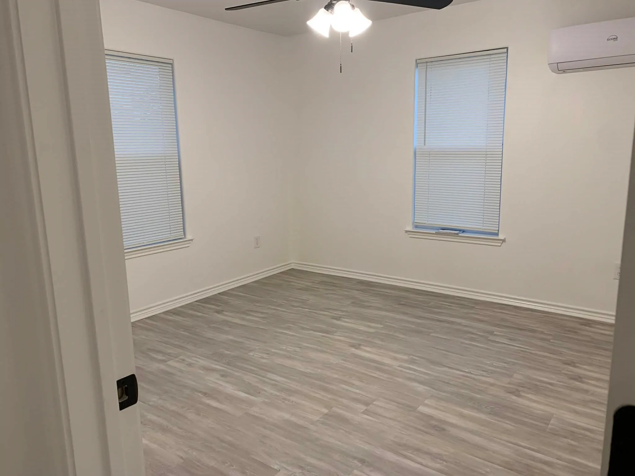 Spare room with light wood finished floors, an AC wall unit, and ceiling fan