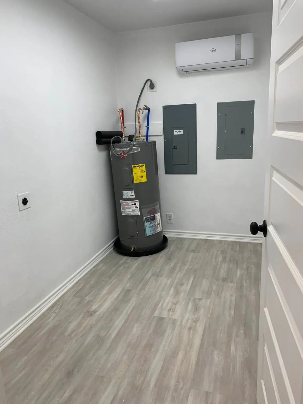 Utilities featuring electric panel, an AC wall unit, and electric water heater
