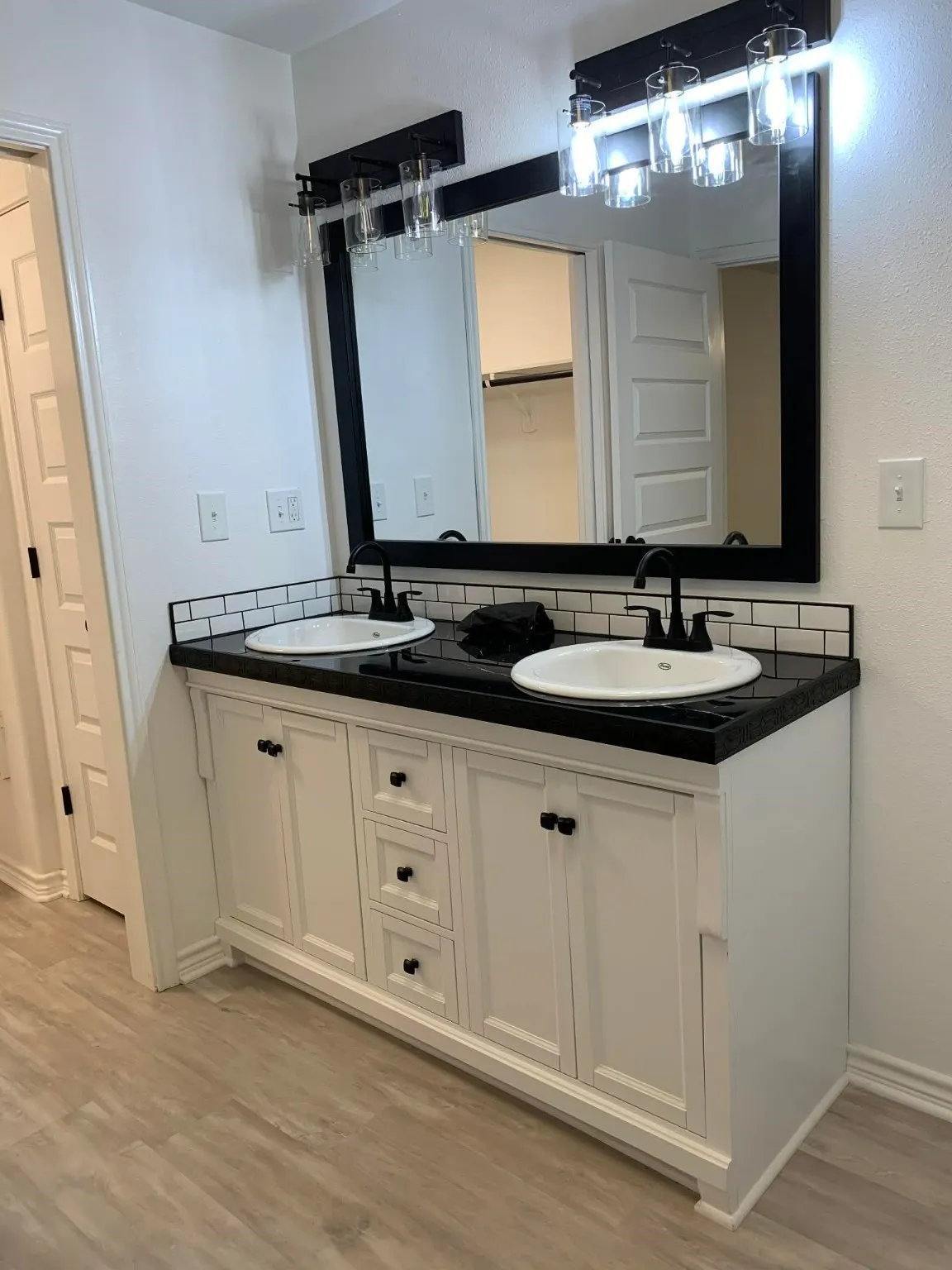 Bathroom featuring double vanity, decorative backsplash, light wood finished floors, and a spacious closet