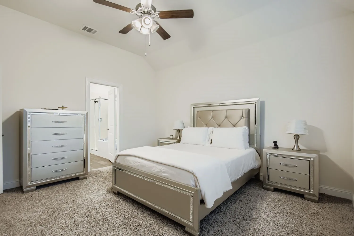 Bedroom featuring lofted ceiling, a ceiling fan, light colored carpet, and connected bathroom