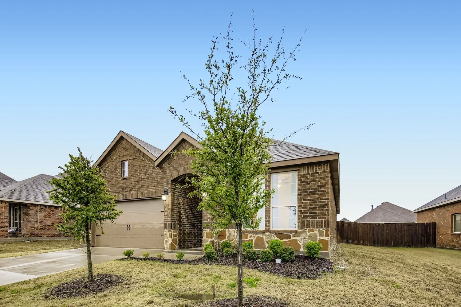 View of front of property featuring brick siding, driveway, and a shingled roof
