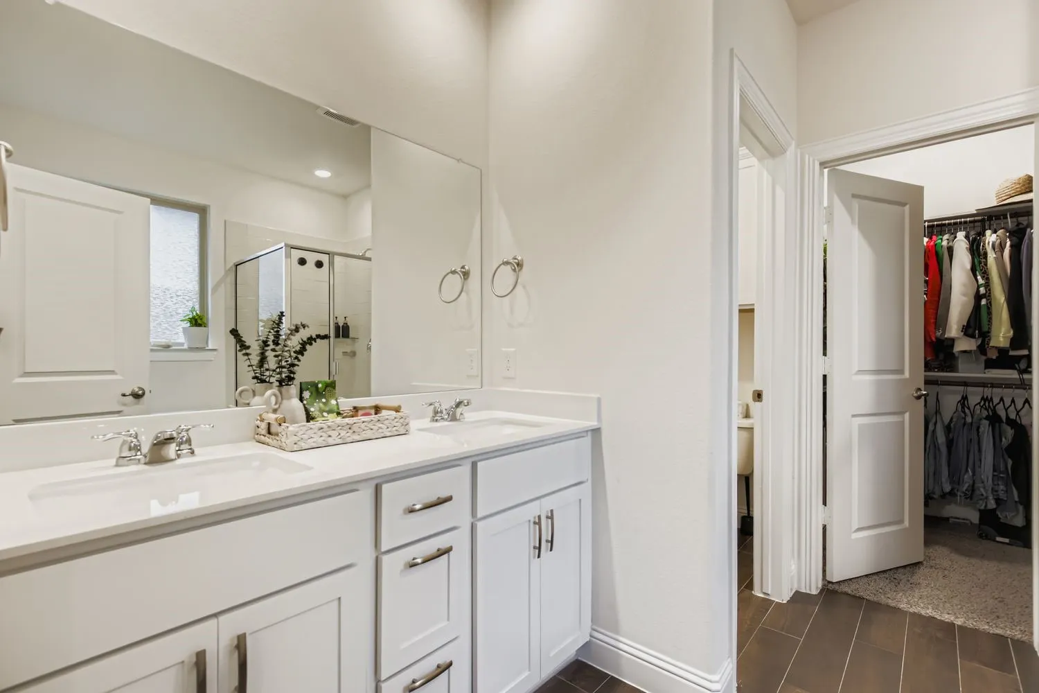 Full bath with a shower stall, double vanity, and a walk in closet