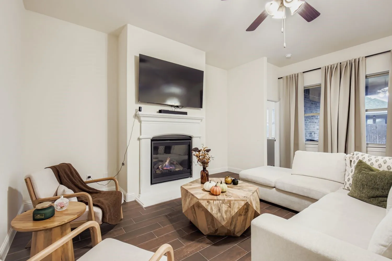 Living room featuring wood finish floors, a glass covered fireplace, and ceiling fan