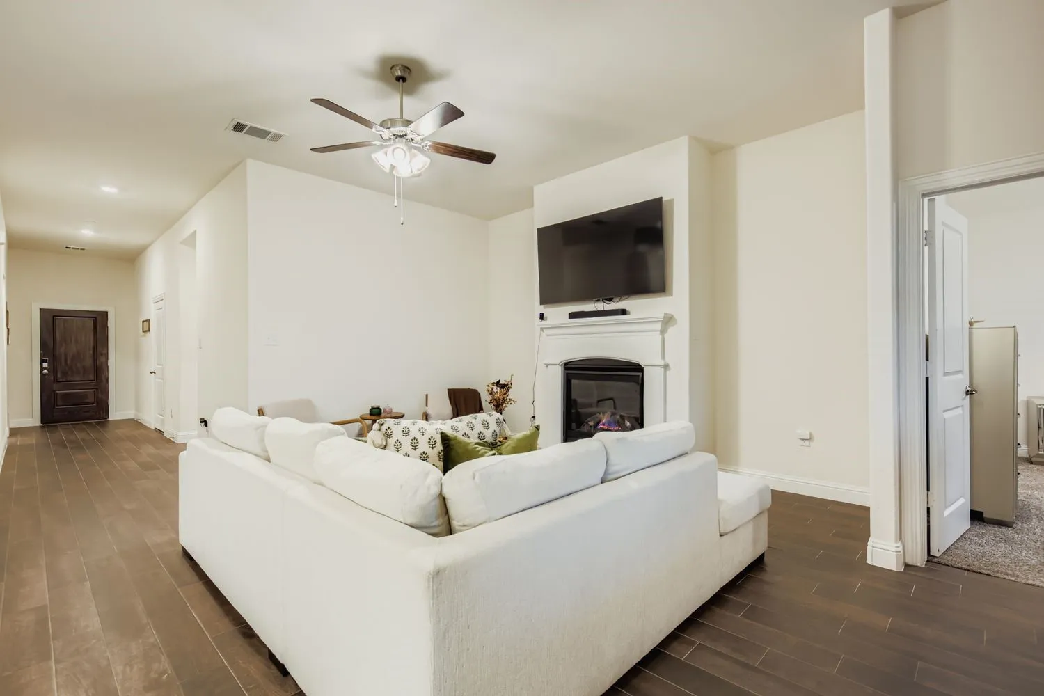Living area with a glass covered fireplace, wood tiled floors, and a ceiling fan