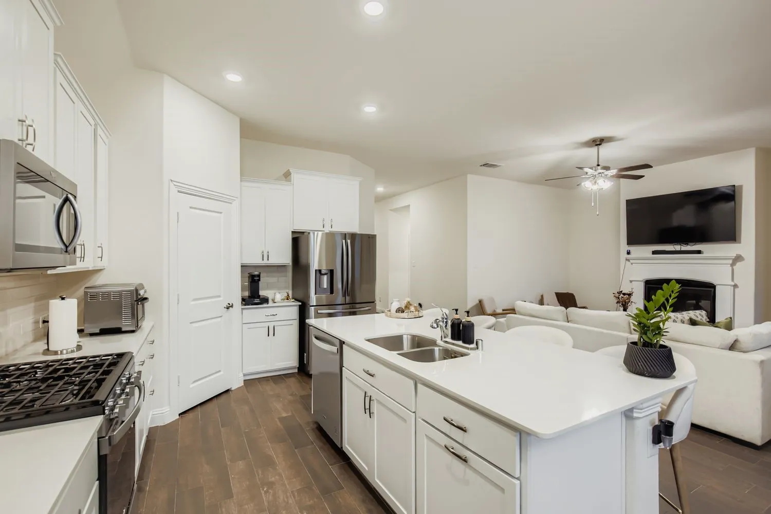 Kitchen featuring white cabinetry, an island with sink, open floor plan, wood tiled floors, and recessed lighting