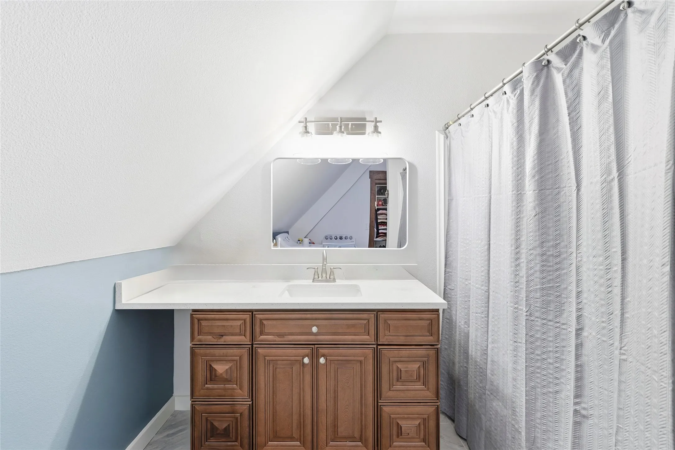 Full bathroom featuring curtained shower, vanity, lofted ceiling, and a textured ceiling