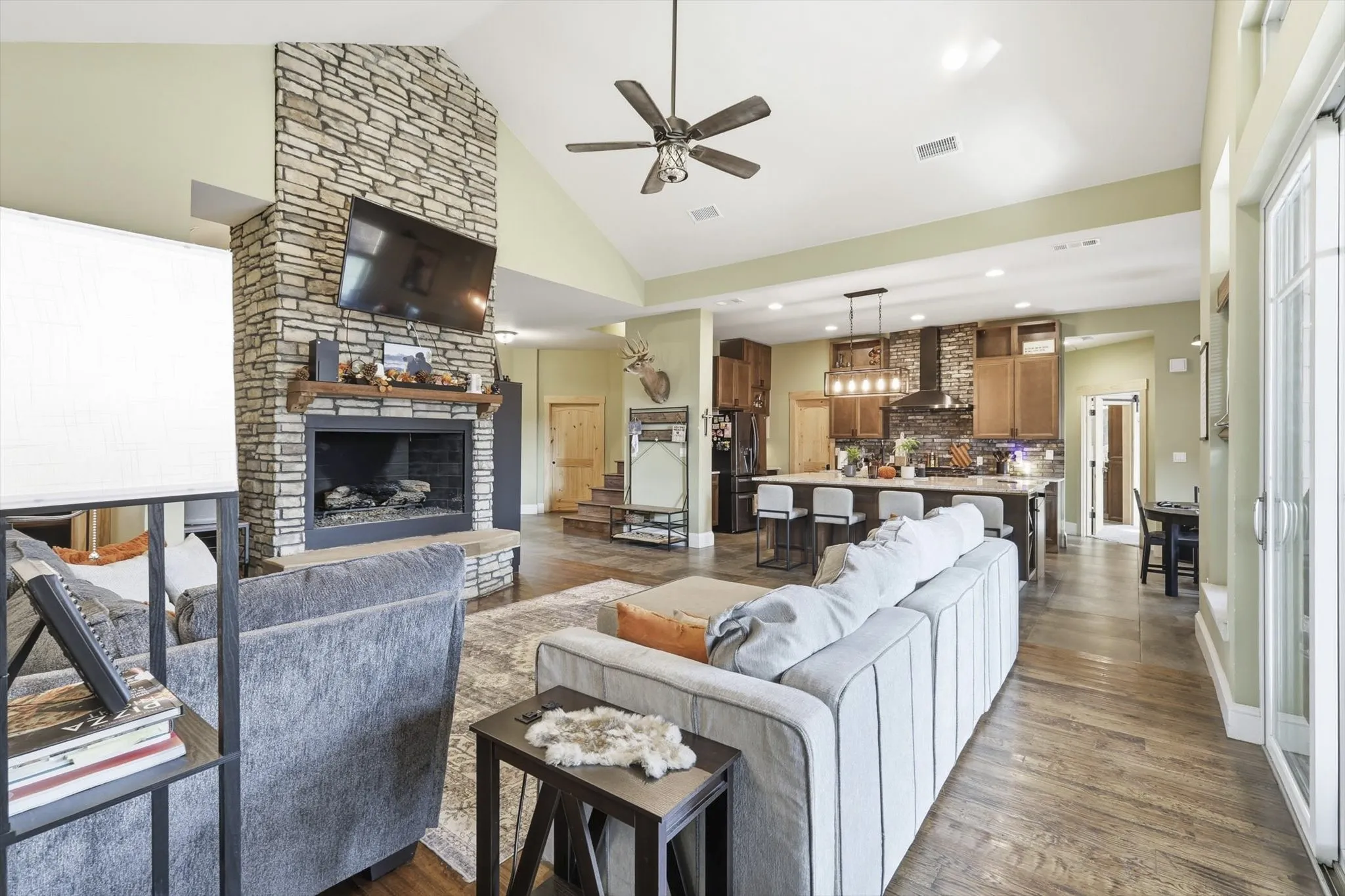 Living area featuring a fireplace, high vaulted ceiling, a ceiling fan, recessed lighting, and dark wood-style flooring