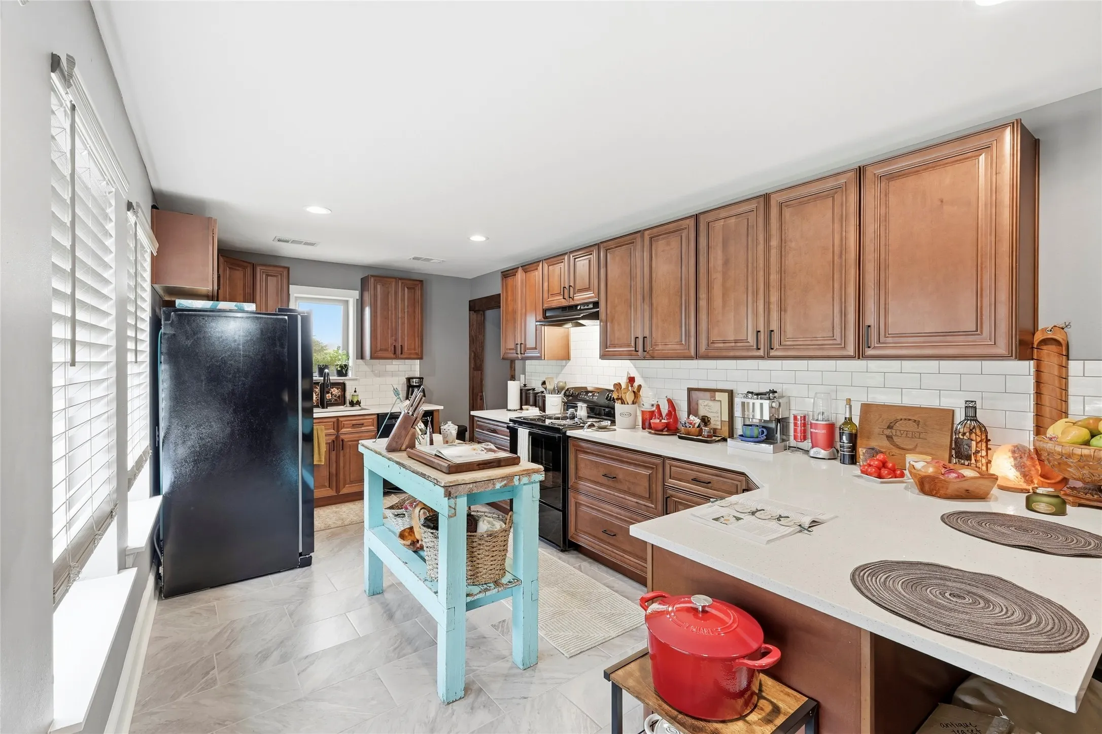 Kitchen featuring black appliances, brown cabinetry, recessed lighting, a peninsula, and decorative backsplash