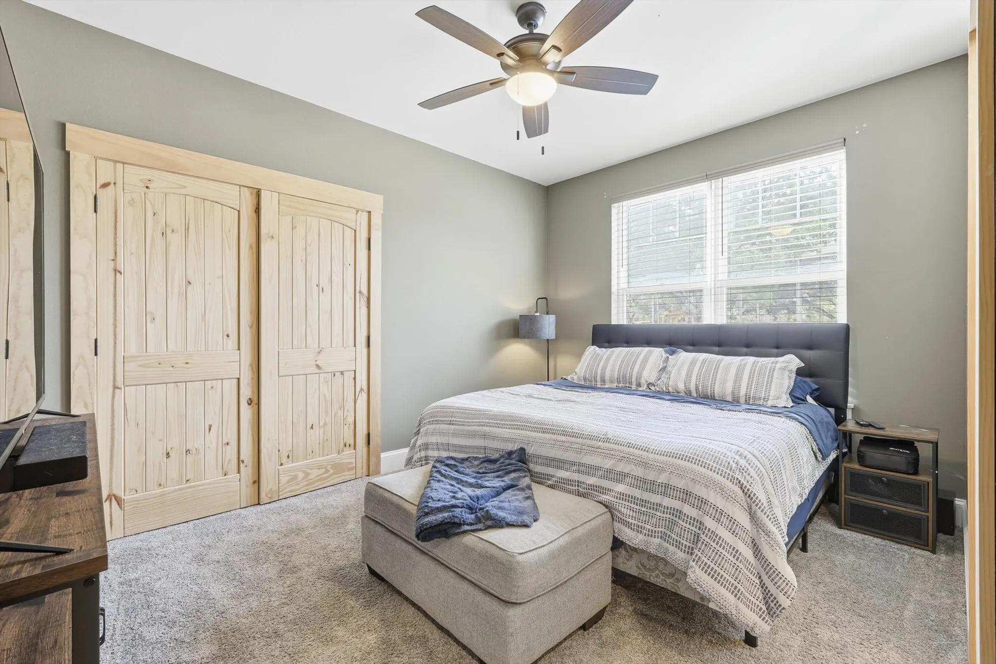 Carpeted bedroom featuring ceiling fan and a closet