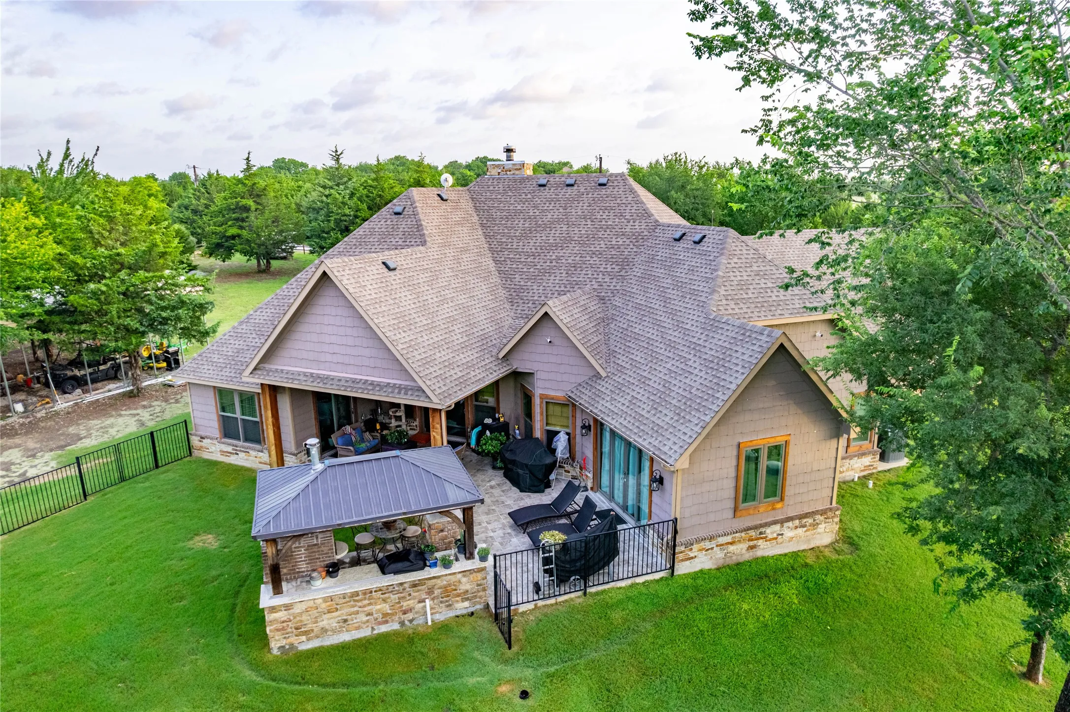 Rear exterior featuring a covered patio, additional detached covered structure, and fenced yard