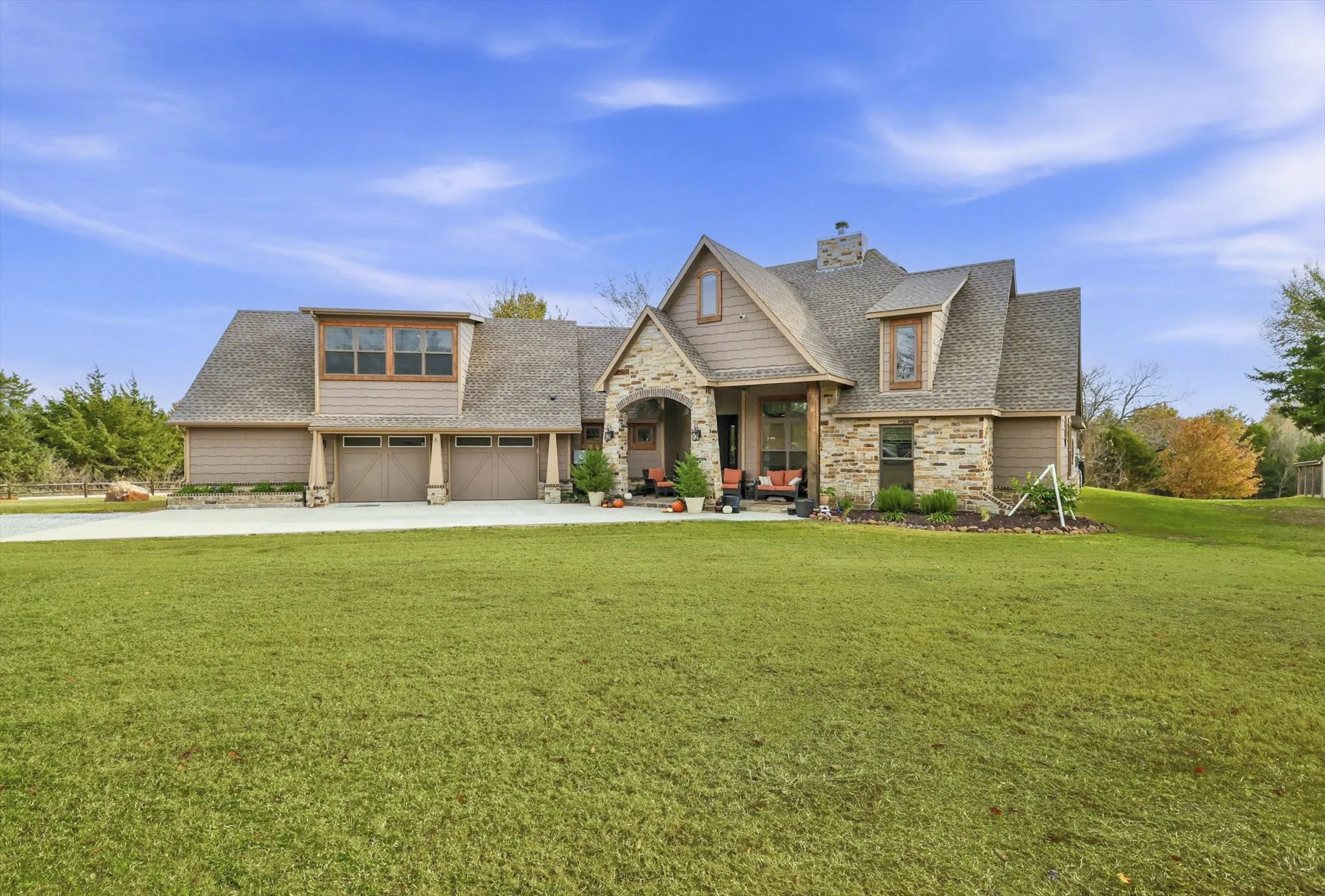 Craftsman inspired home featuring stone siding, a front lawn, roof with shingles, driveway, and a chimney