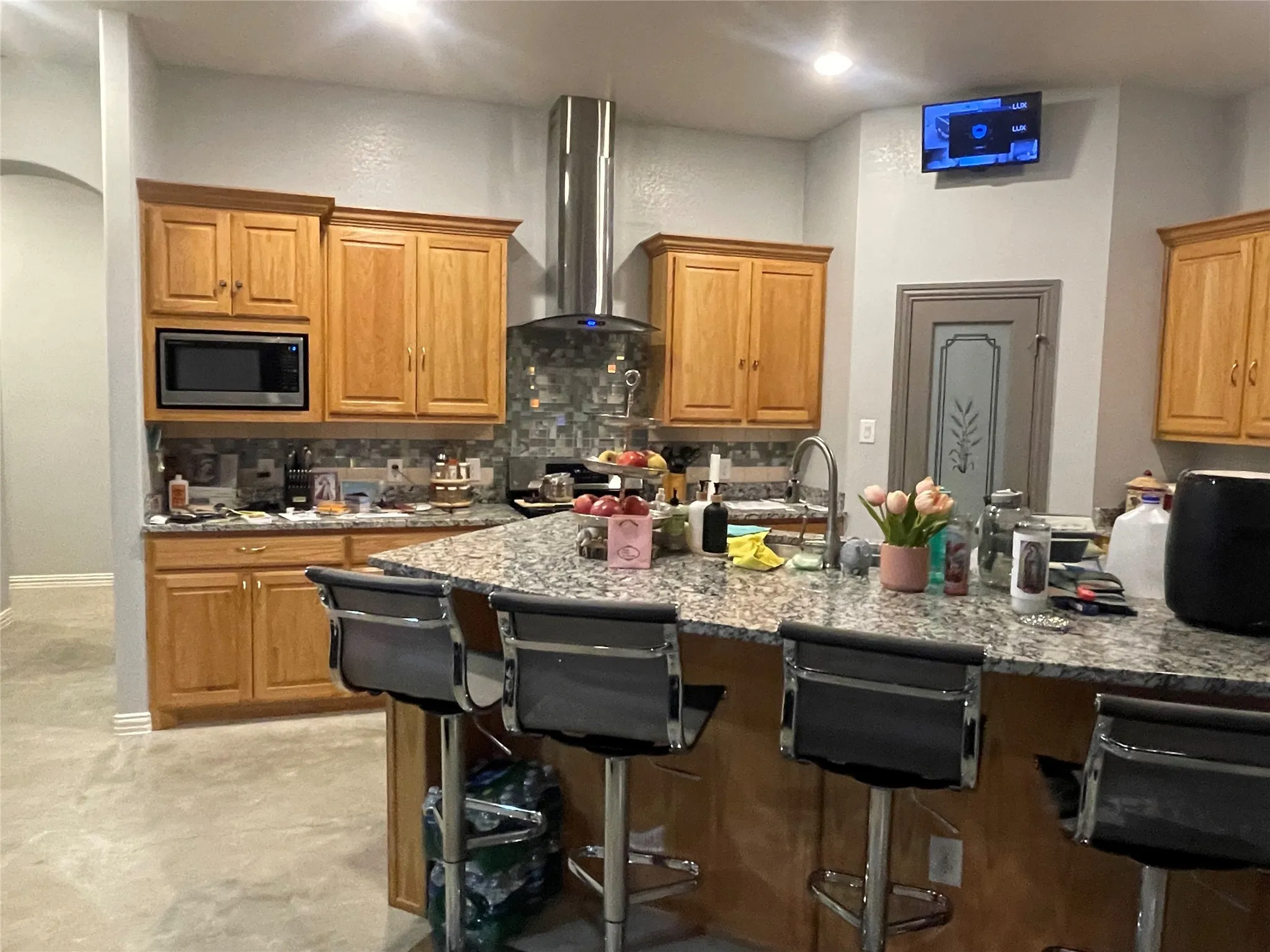 Kitchen featuring brown cabinets, decorative backsplash, a breakfast bar, and light stone countertops