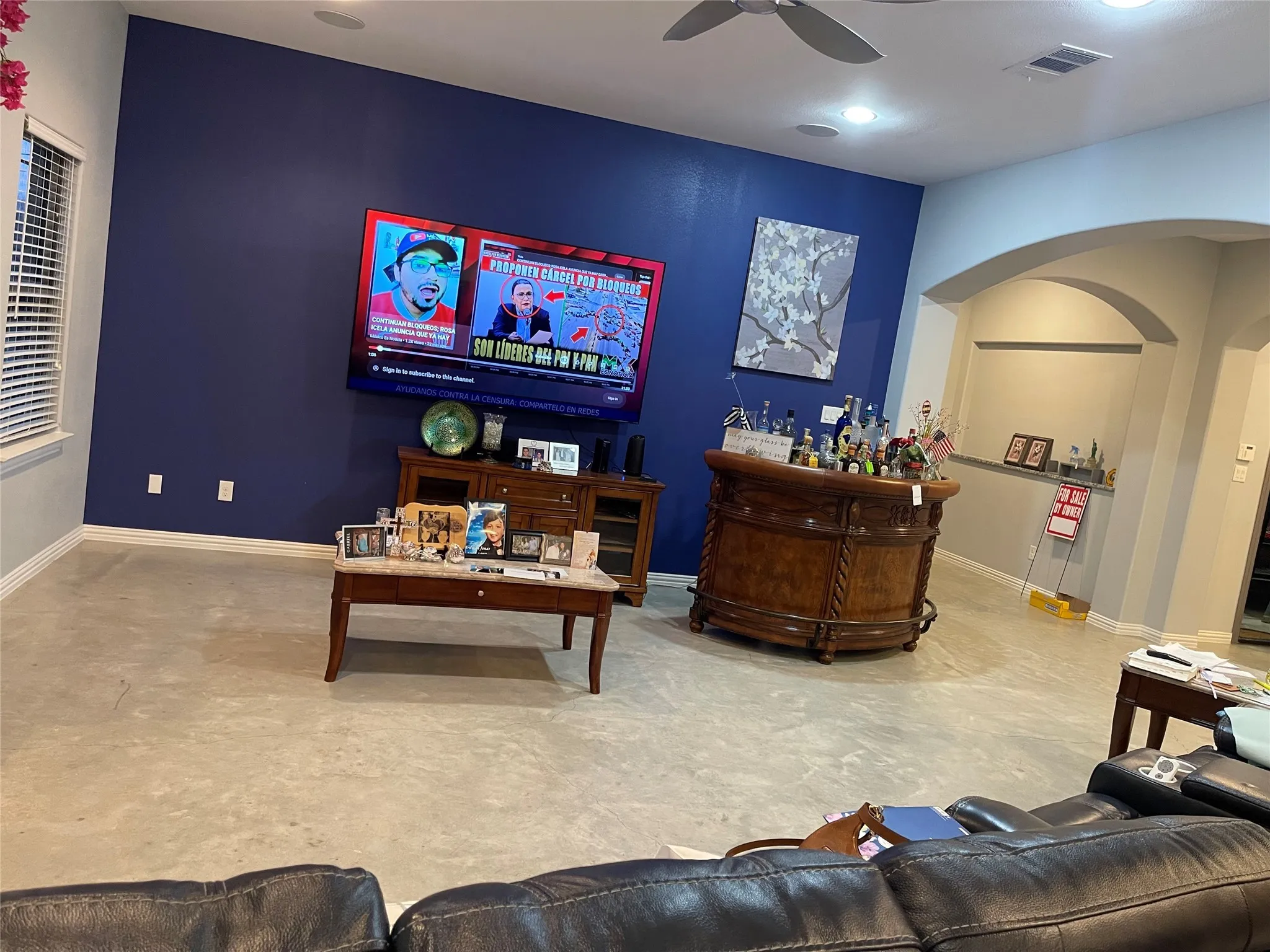 Living room with a dry bar, arched walkways, and a ceiling fan