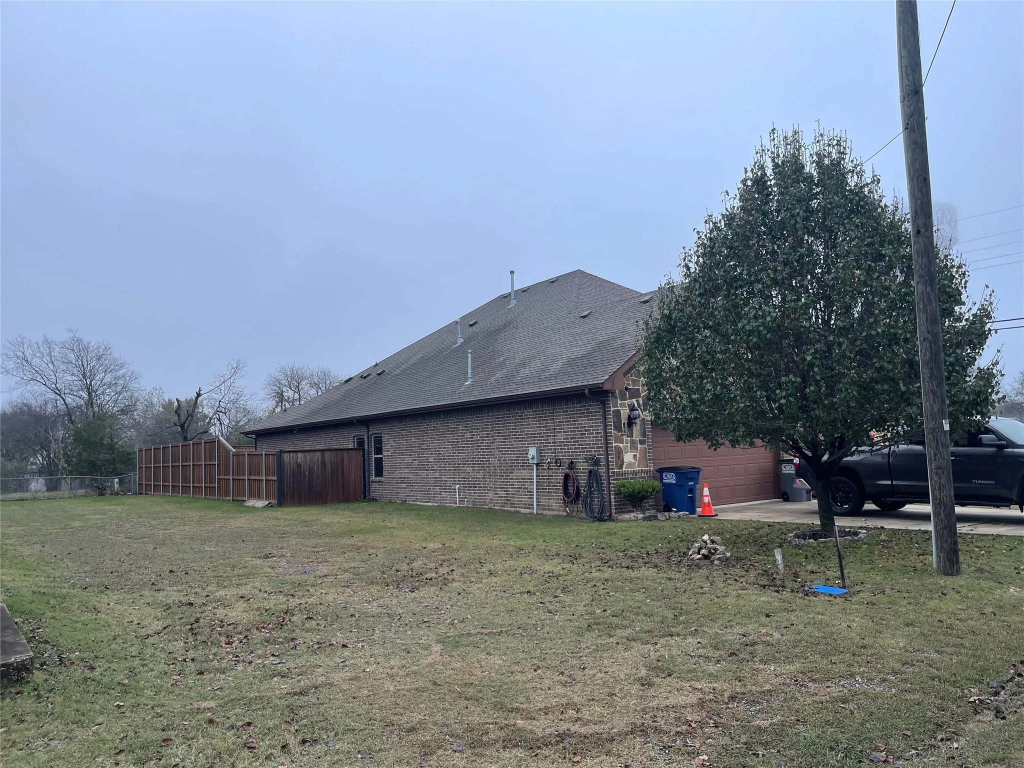 View of property exterior featuring brick siding, roof with shingles, an attached garage, and concrete driveway
