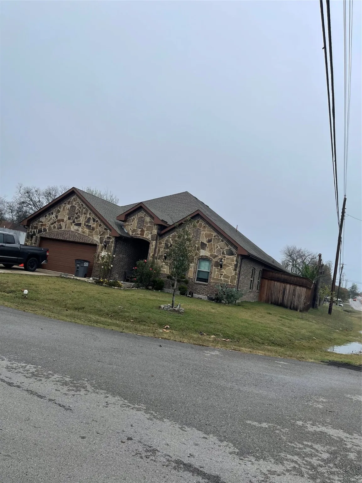 View of front of house with stone siding, a front yard, and an attached garage
