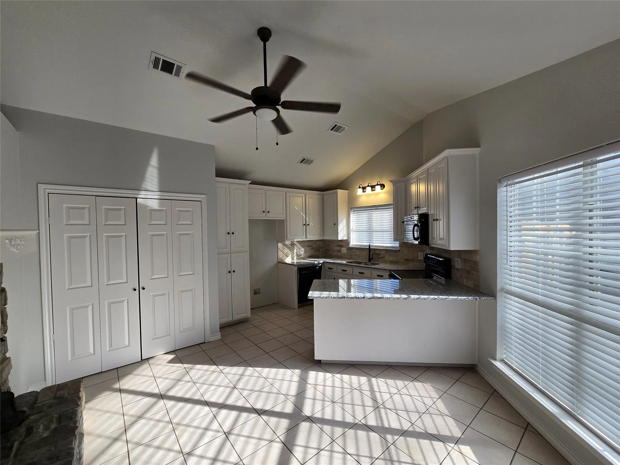 Kitchen featuring a peninsula, white cabinets, ceiling fan, light tile patterned floors, and lofted ceiling