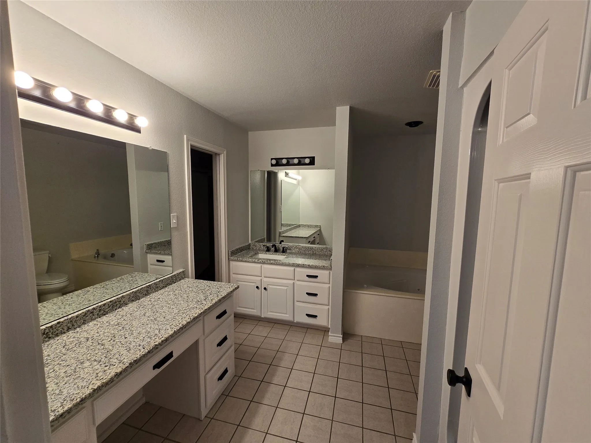 Full bath with a bath, vanity, a textured ceiling, and light tile patterned floors