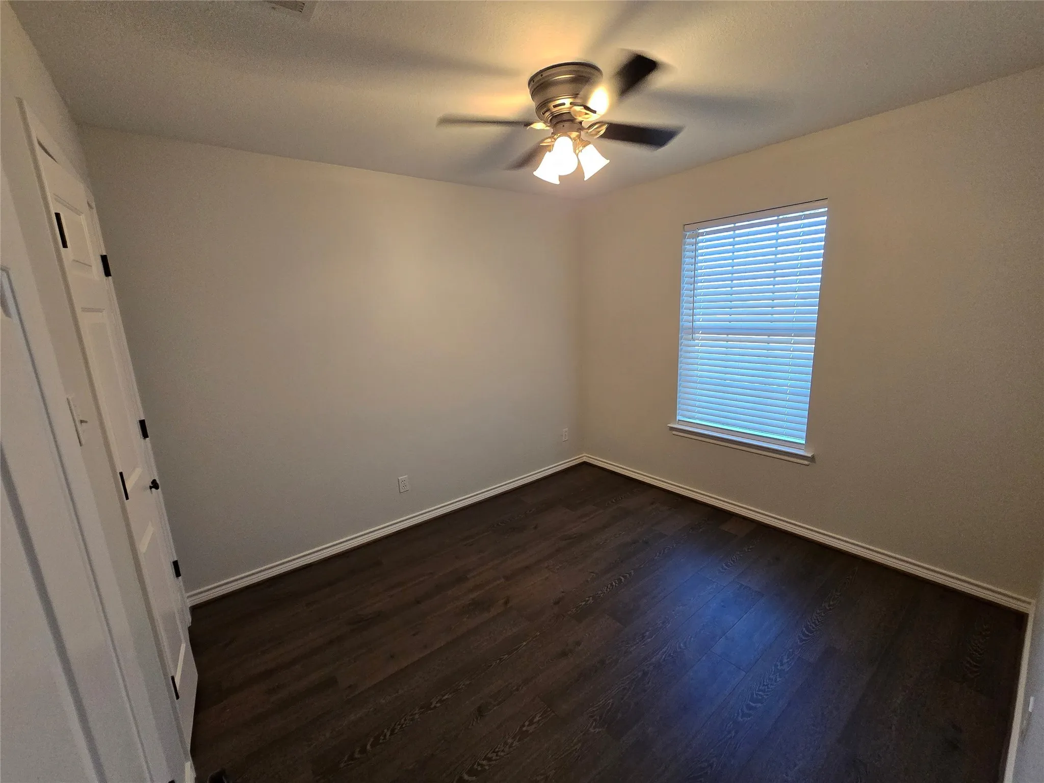 Spare room with dark wood finished floors, a ceiling fan, and a textured ceiling