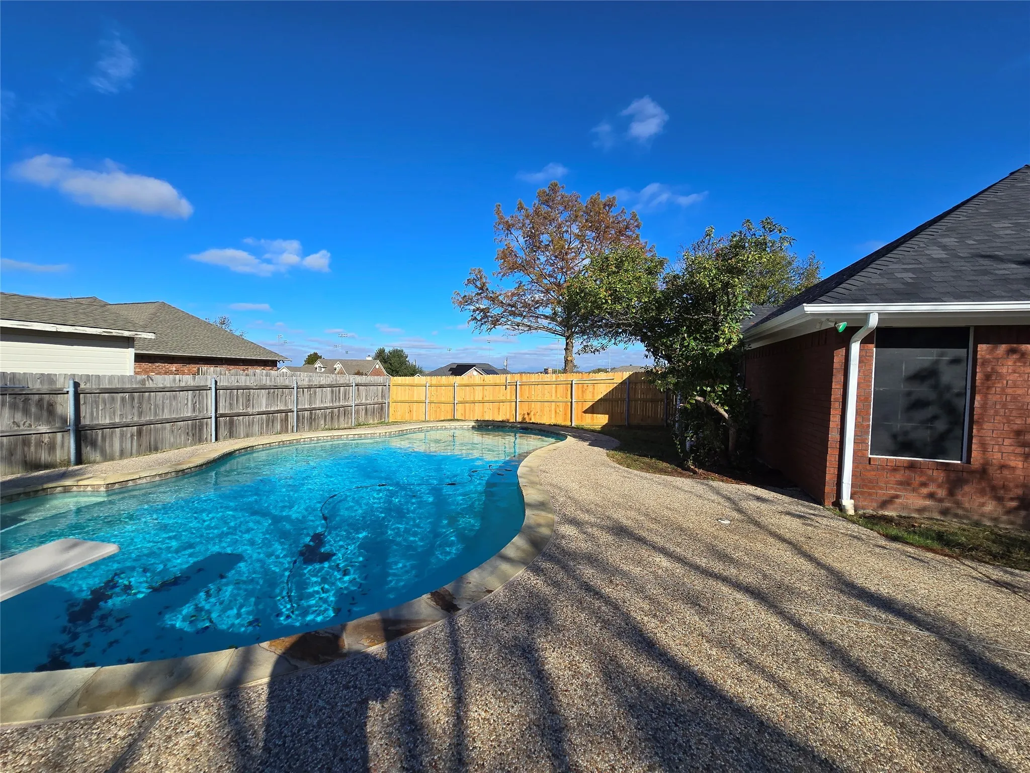 View of swimming pool with a fenced backyard and a diving board