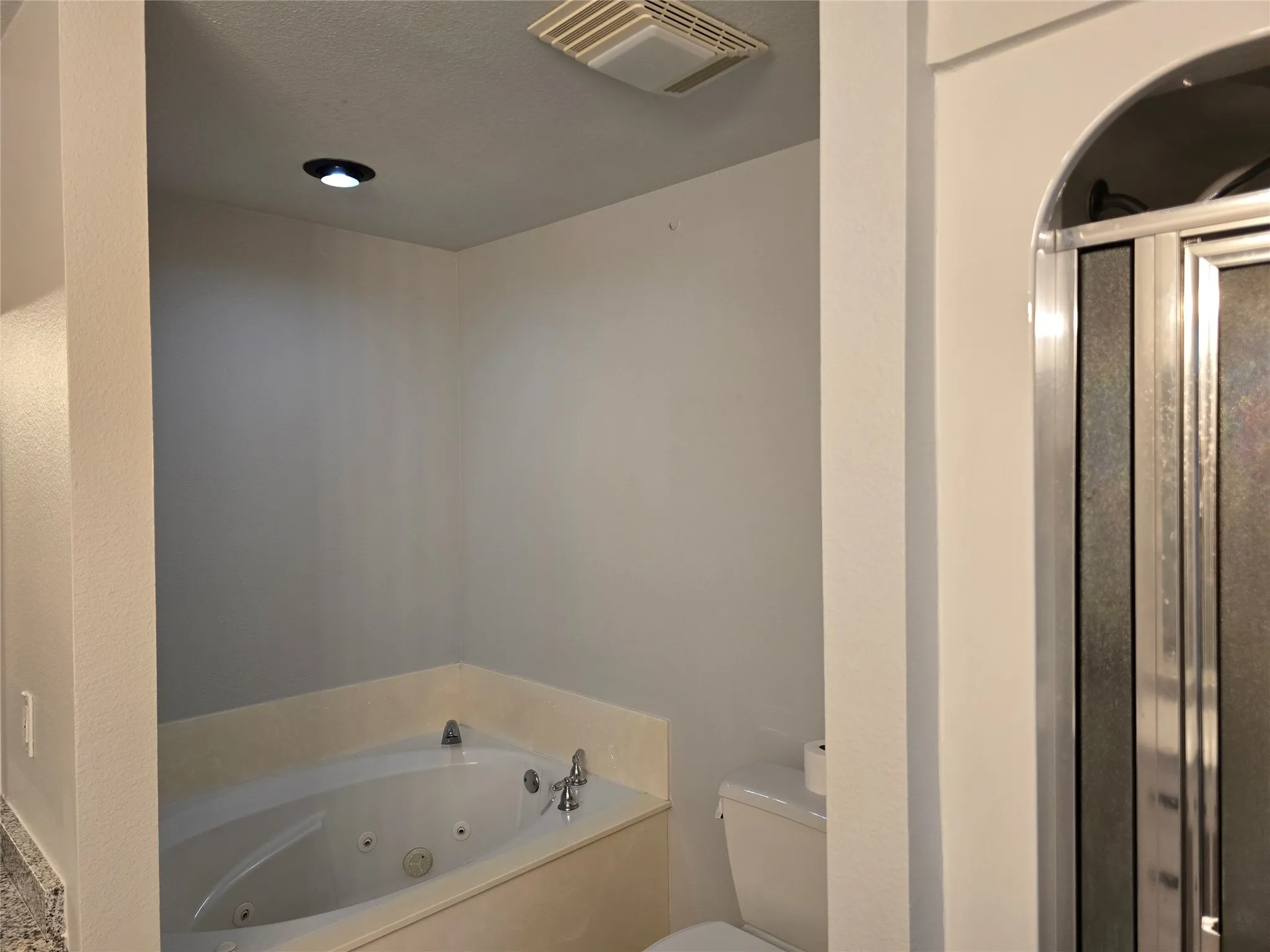 Bathroom featuring a jetted tub, a stall shower, and a textured ceiling