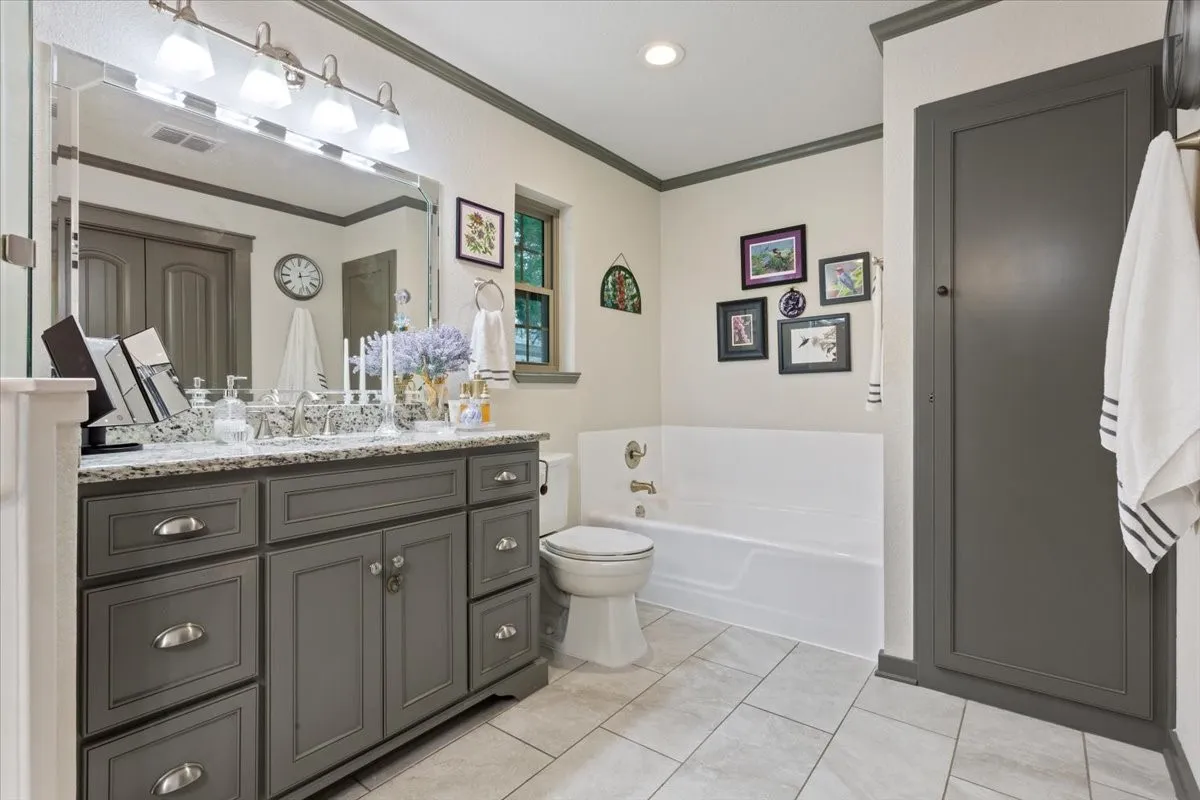 Full bathroom featuring ornamental molding, vanity, a garden tub, and light tile patterned floors