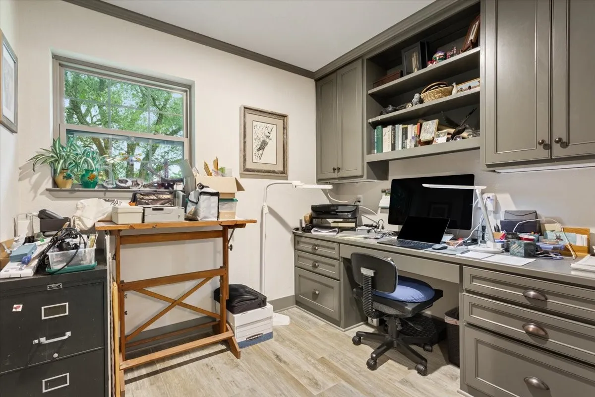 Home office with built in desk, ornamental molding, and light wood-style floors