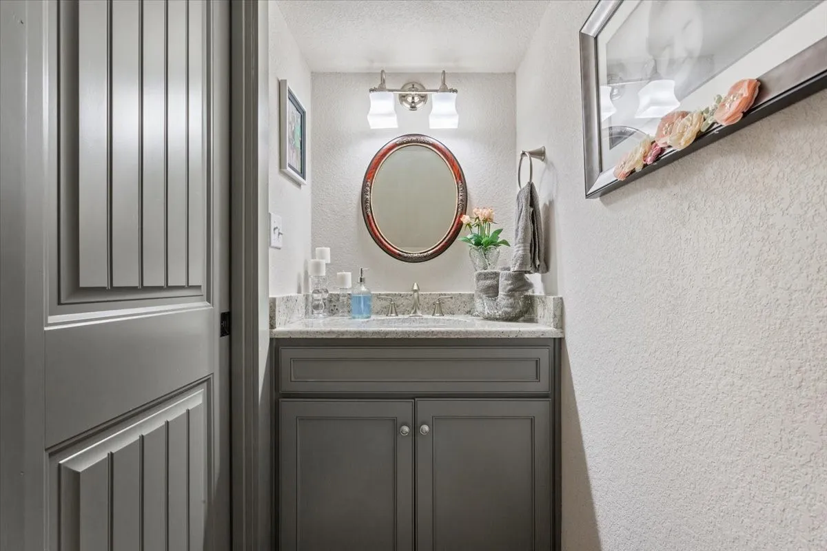 Half bath with a textured wall, vanity, and a textured ceiling