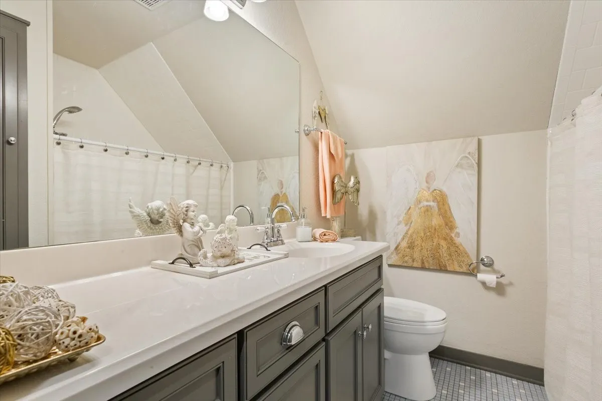 Bathroom featuring a shower with shower curtain, vanity, vaulted ceiling, and dark tile patterned flooring