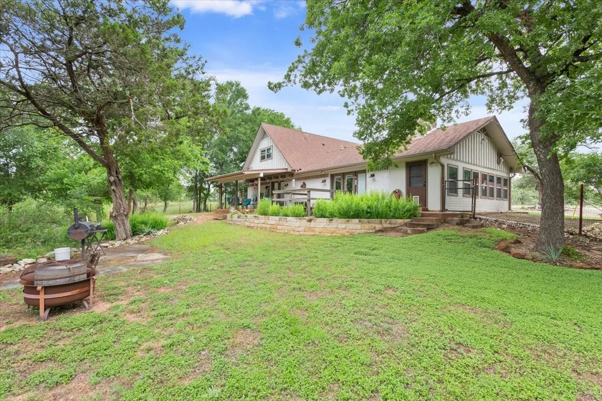 Rear view of property featuring a lawn and roof with shingles