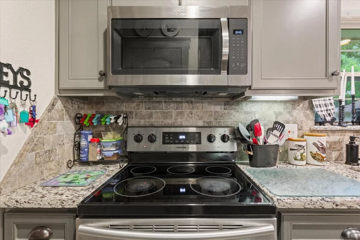 Kitchen featuring stainless steel appliances, gray cabinetry, and decorative backsplash