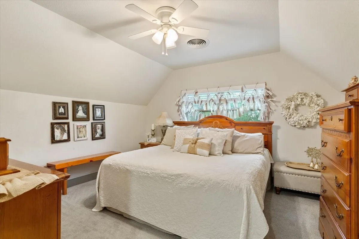 Carpeted bedroom with ceiling fan and lofted ceiling