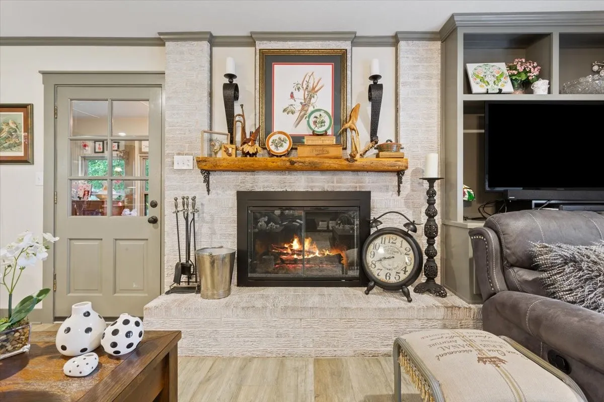 Living area featuring a fireplace, wood finished floors, and crown molding