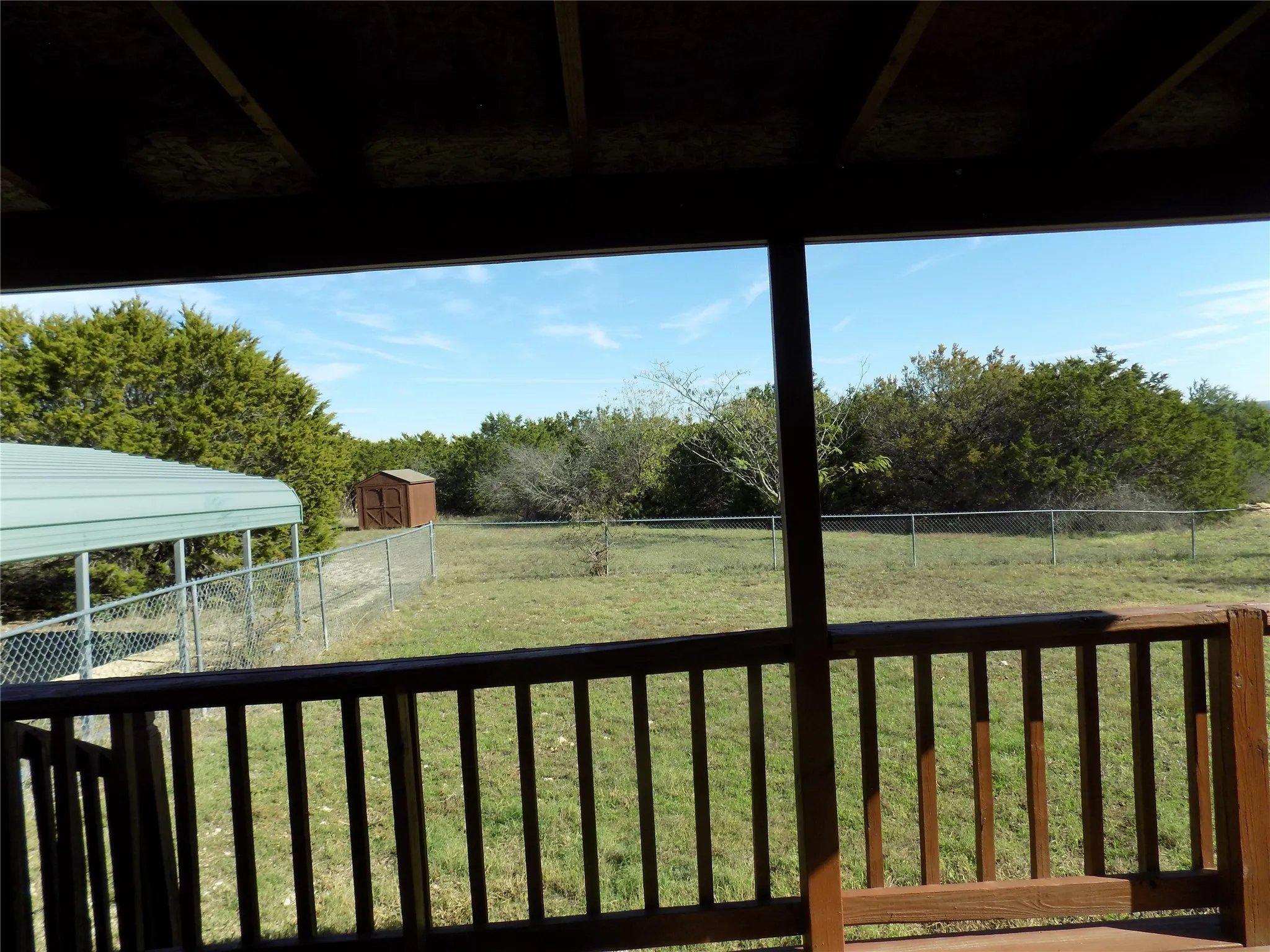 Another view from the back deck, showing the 2-car carport and special storage building.  The fencing is a great size.