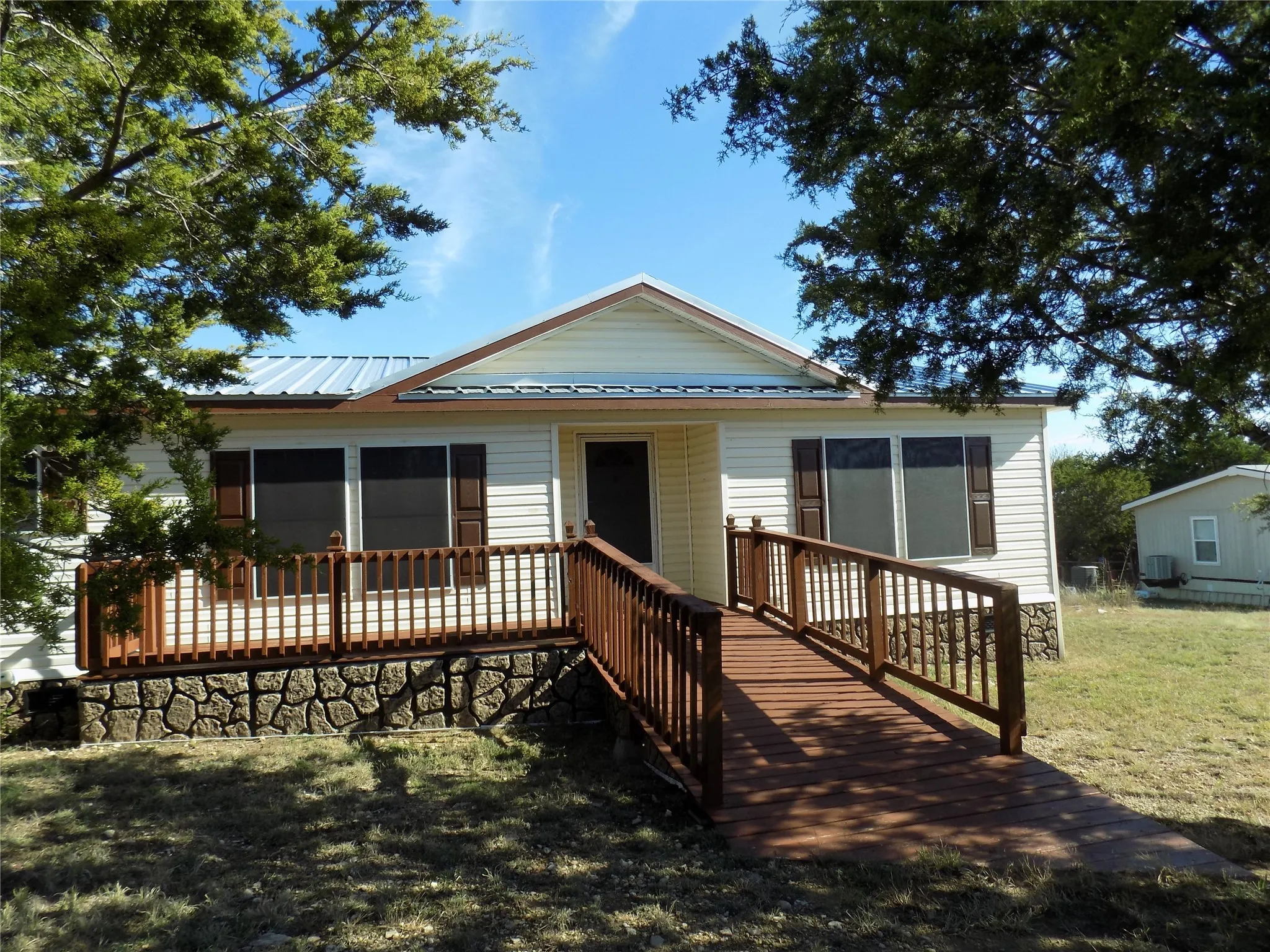 Back of property with a deck, a yard, and a metal roof