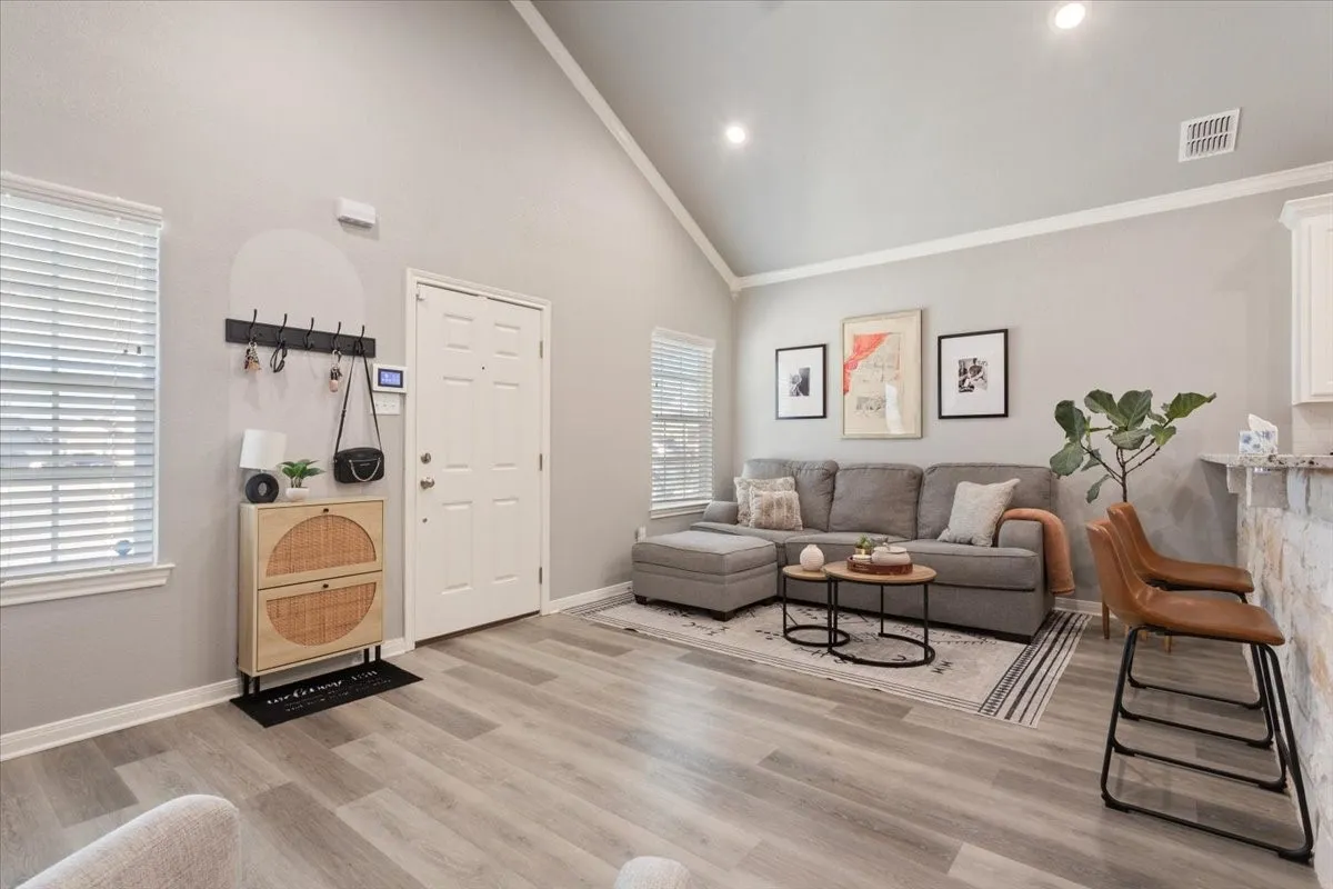 Living room with high vaulted ceiling and light wood-type flooring