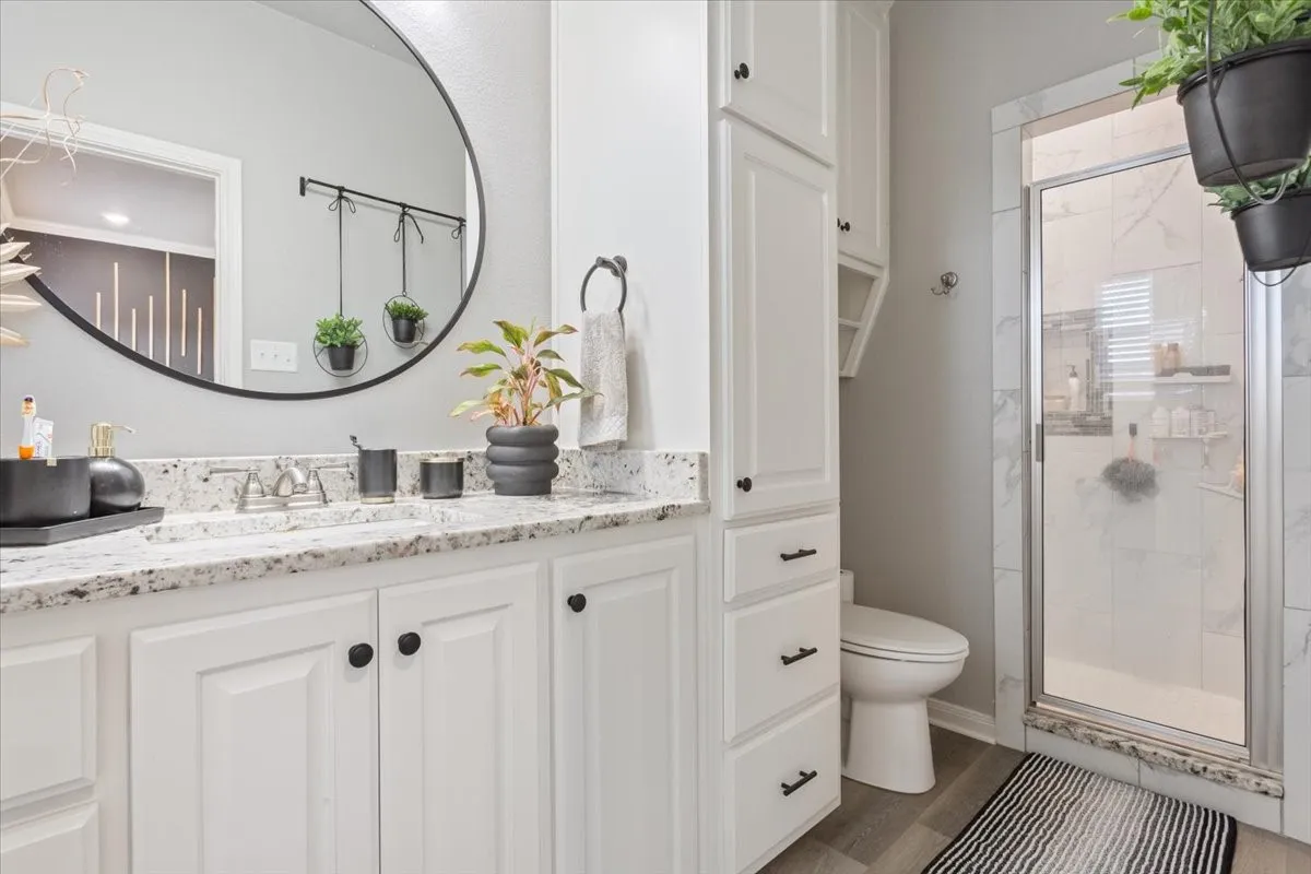 Bathroom with vanity, a shower stall, and dark wood finished floors