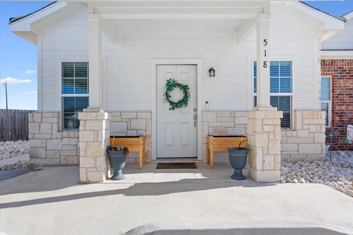 View of exterior entry with stone siding and covered porch