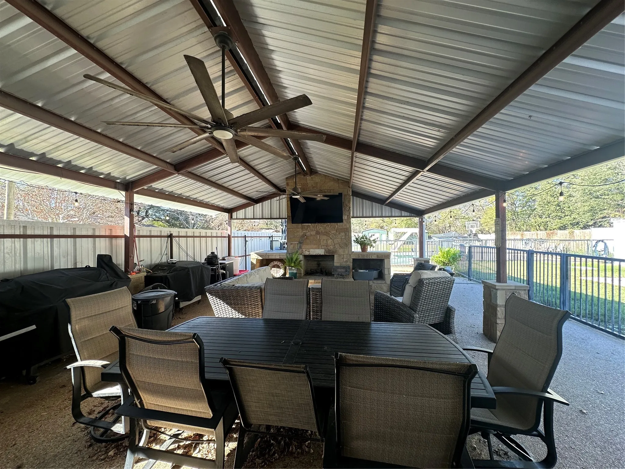 Fenced backyard featuring ceiling fan, outdoor dining area, an outdoor stone fireplace, and a patio area