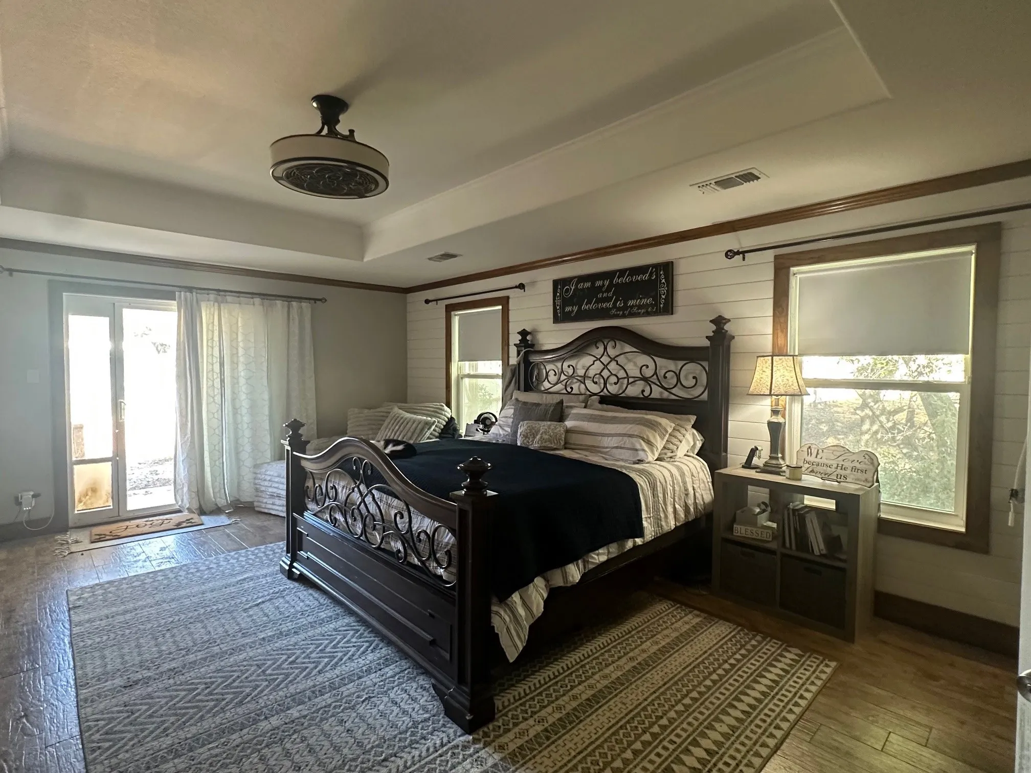 Bedroom with wood-type flooring, a tray ceiling, wood walls, and crown molding