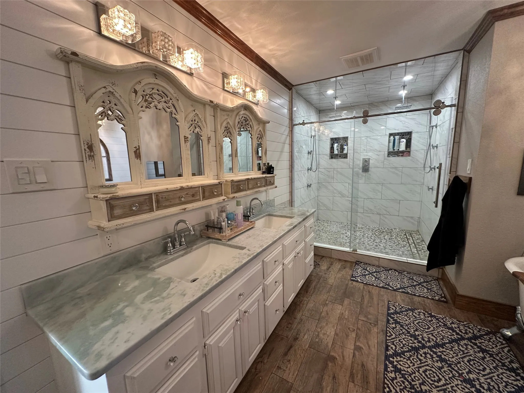 Bathroom with double vanity, dark wood finished floors, a shower stall, and crown molding