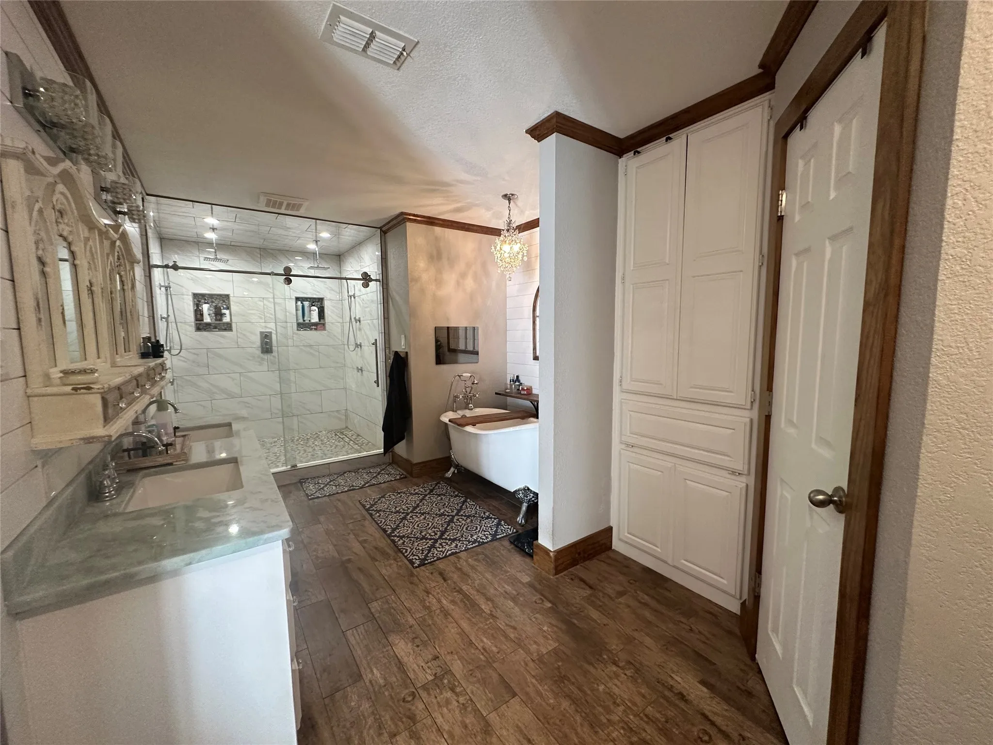 Bathroom with a stall shower, a freestanding tub, a textured ceiling, dark wood-style floors, and vanity